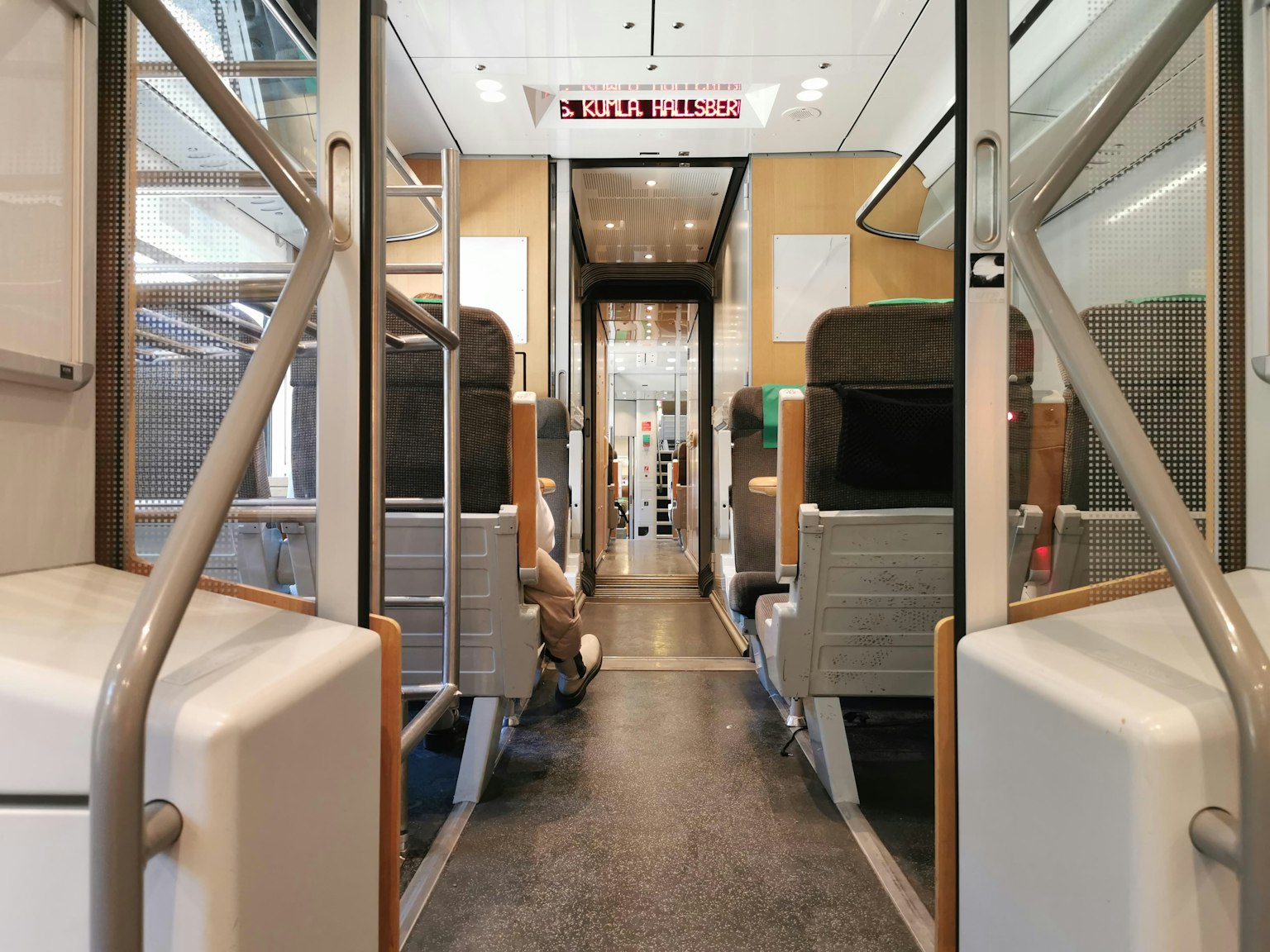 Vista interior de un tren moderno que muestra asientos y pasillo