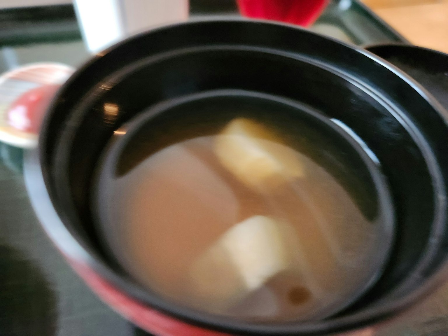 Soupe miso dans un bol noir avec des morceaux de tofu