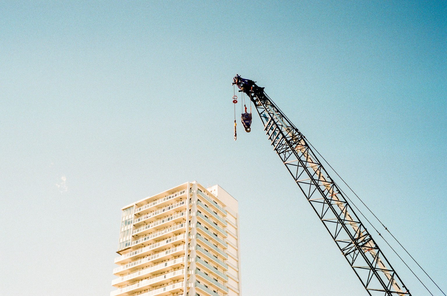 Kran über einem Hochhaus mit klarem blauen Himmel