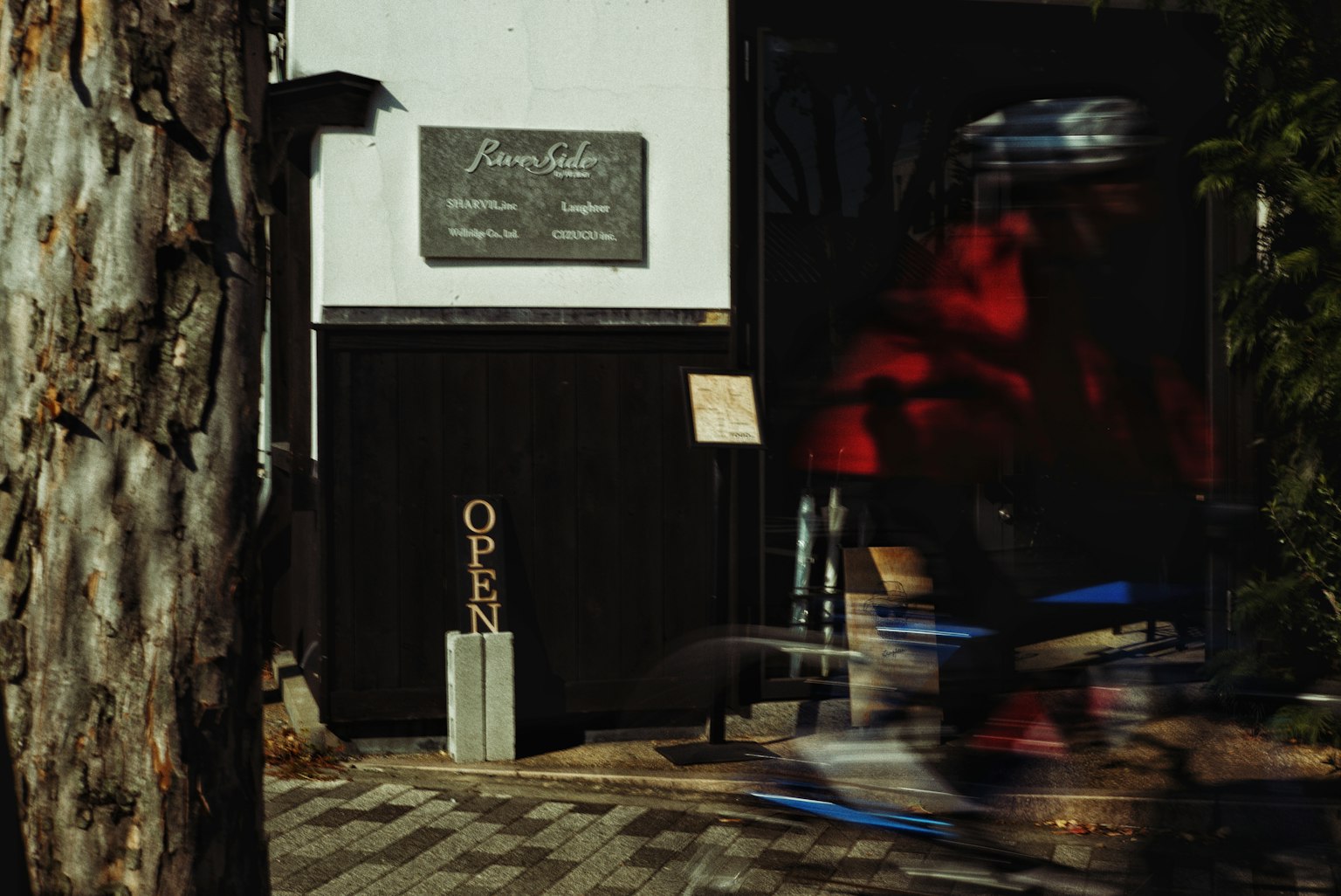 Un cycliste passant devant l'extérieur d'un café avec un tronc d'arbre