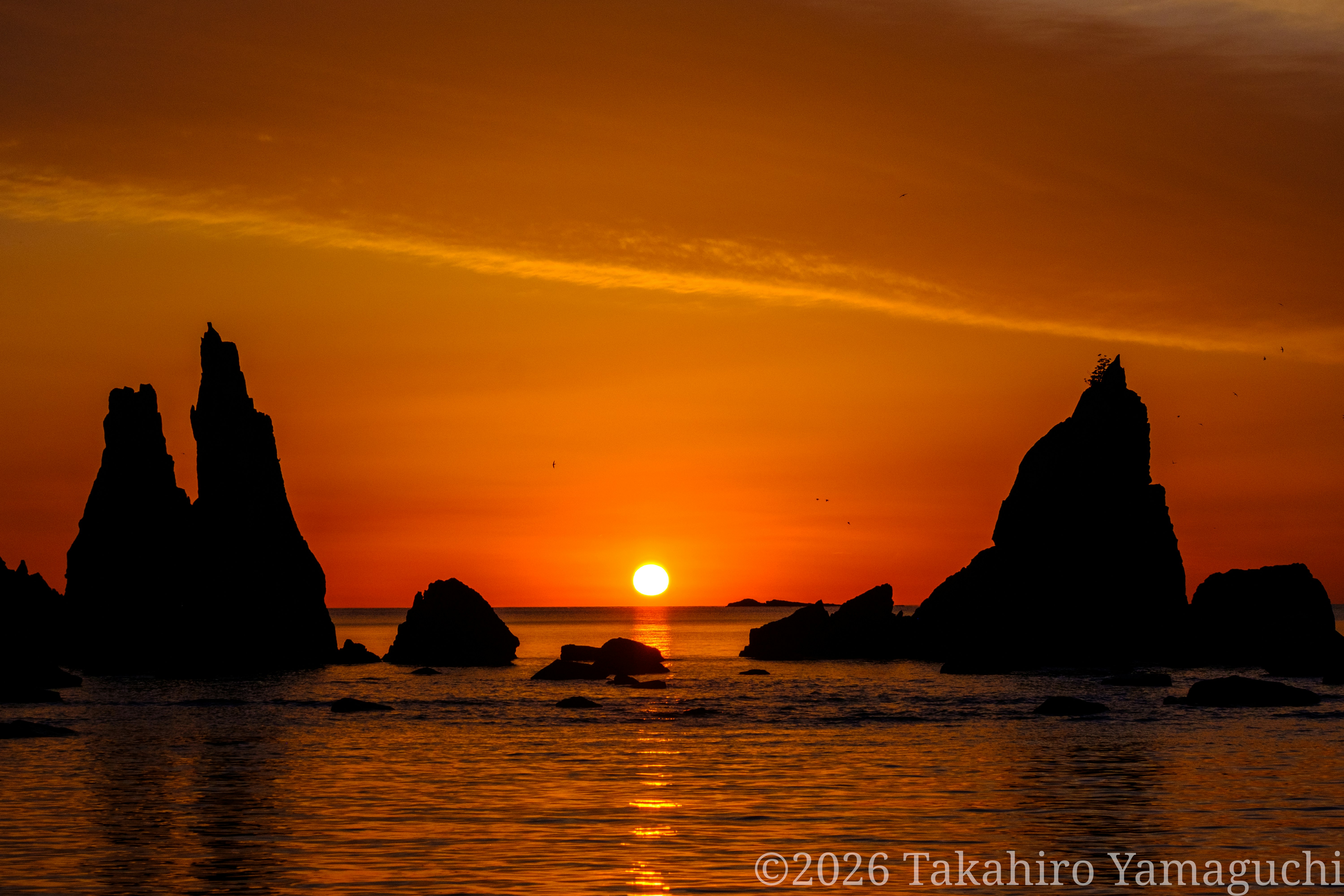夕日に照らされる海と岩のシルエット