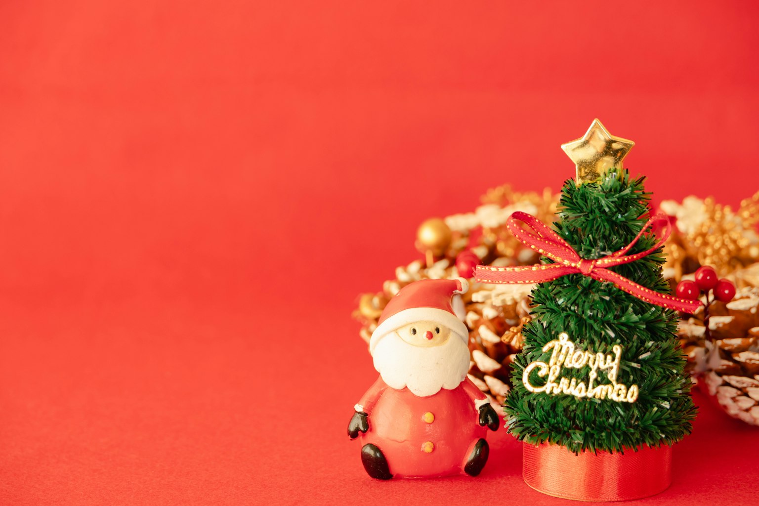 Santa-Figur und kleiner Weihnachtsbaum vor rotem Hintergrund