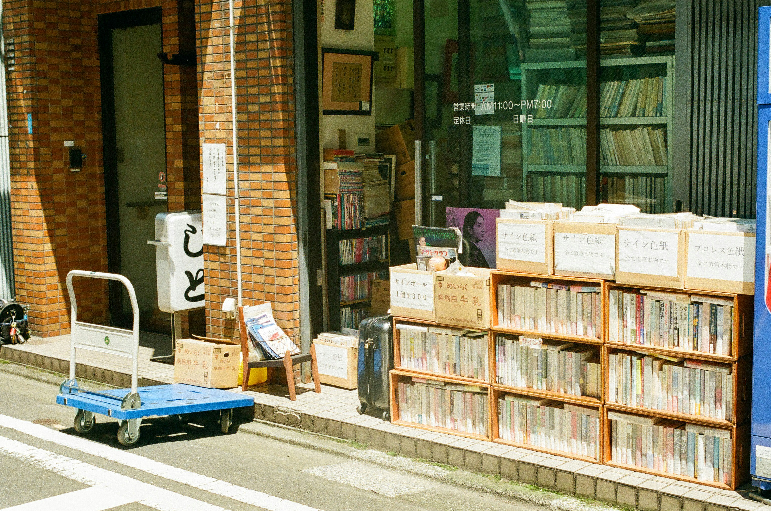 bookshelves and boxed books lined up outside a used bookstore on a narrow street
