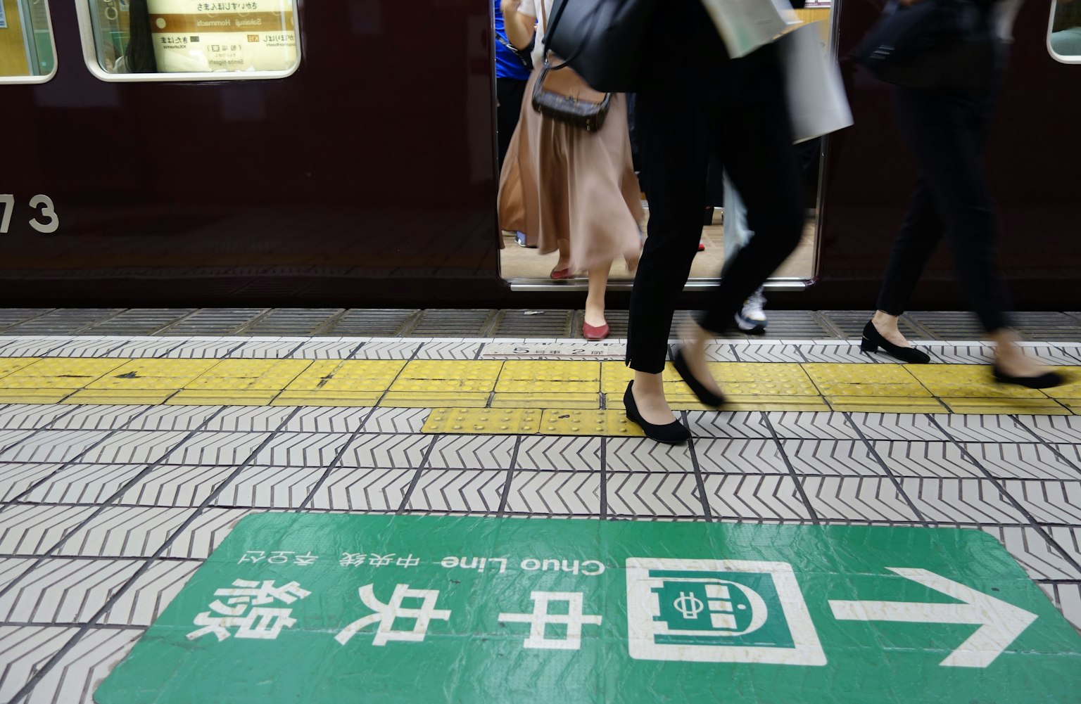 Passeggeri che scendono da un treno con segnaletica direzionale sulla banchina