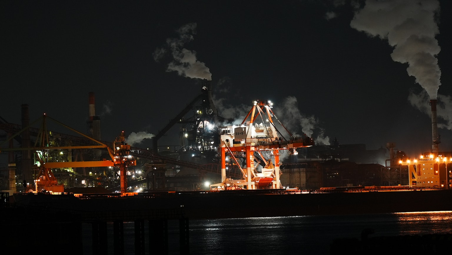 夜间工业起重机和烟囱的景观