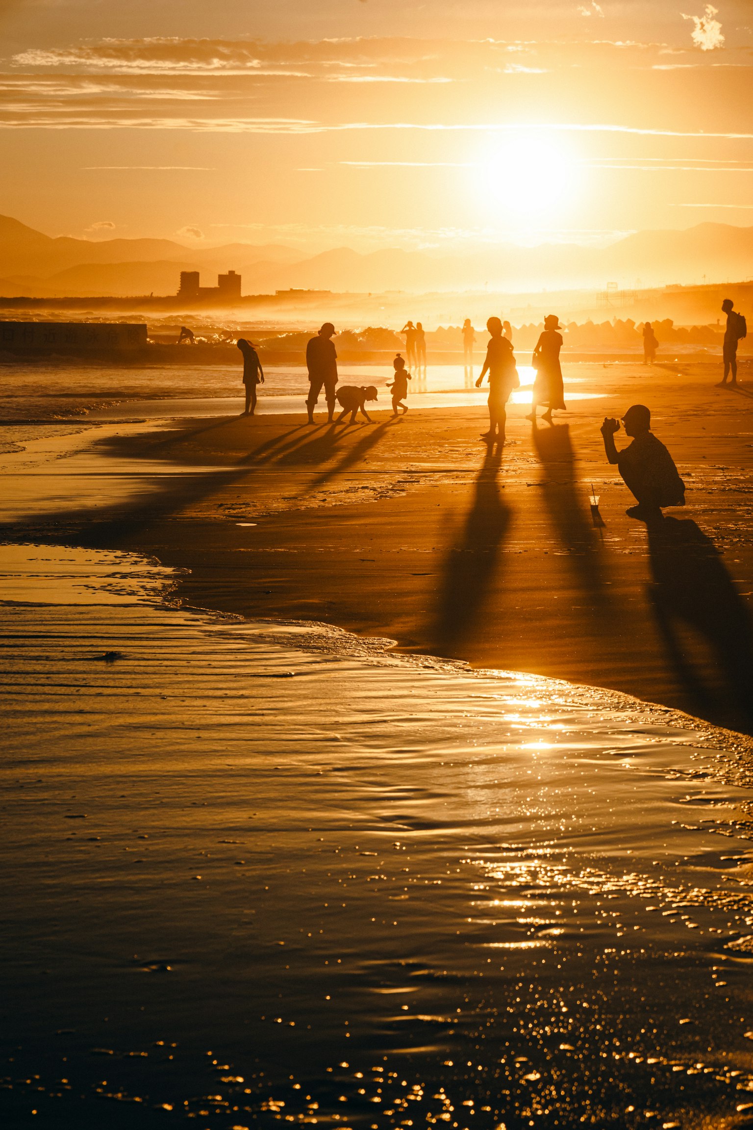 เงาของผู้คนเดินอยู่บนชายหาดในขณะพระอาทิตย์ตก