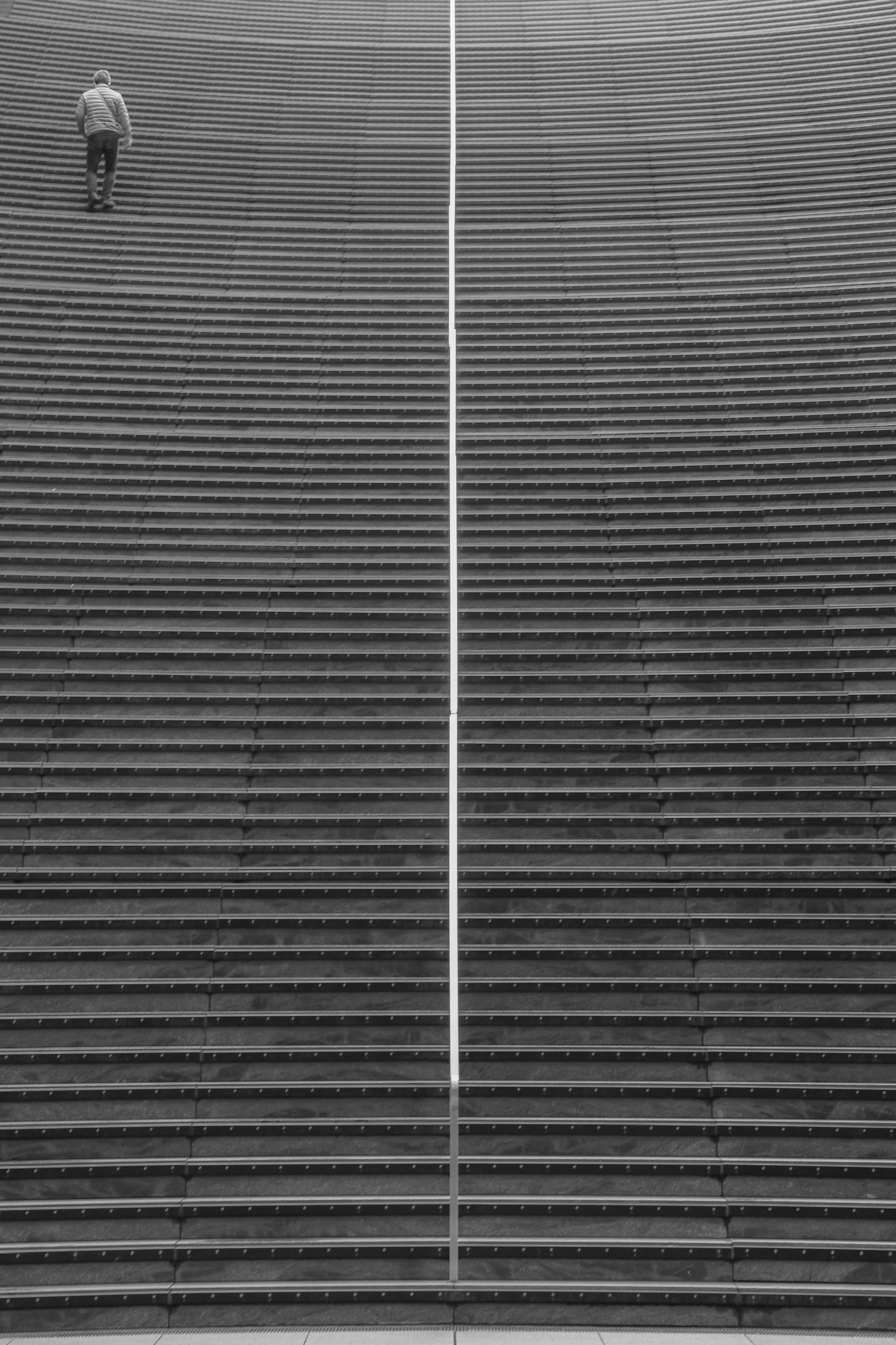 A person walking up a series of parallel stairs in black and white