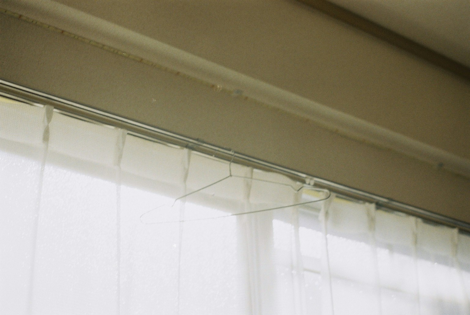 Nahaufnahme von durchsichtigen weißen Vorhängen nahe einem Fenster mit einer einfachen oberen Schiene