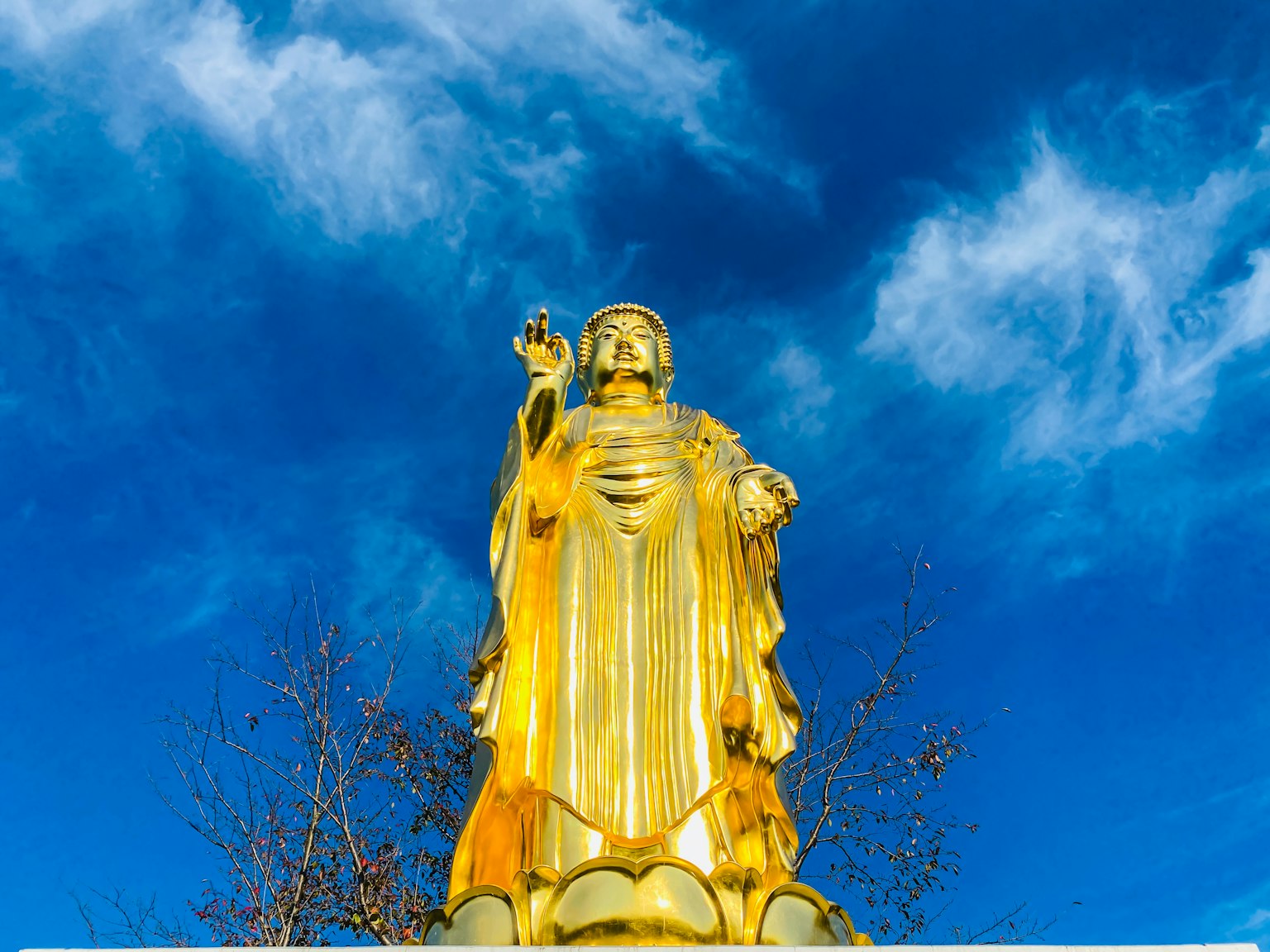 Vista completa di una statua dorata di Guanyin sotto un cielo blu