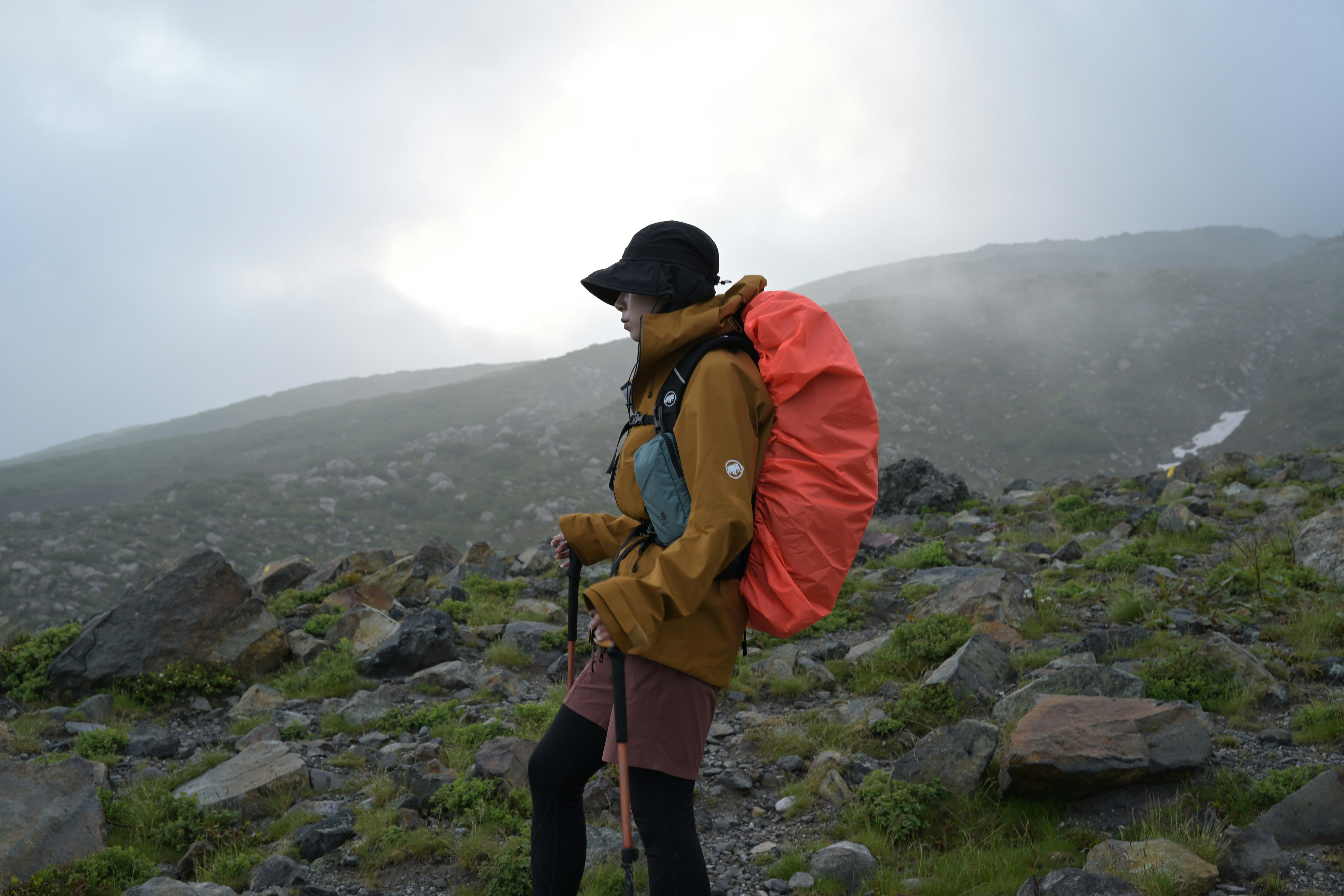 hiker walking along a rocky mountain trail in mist