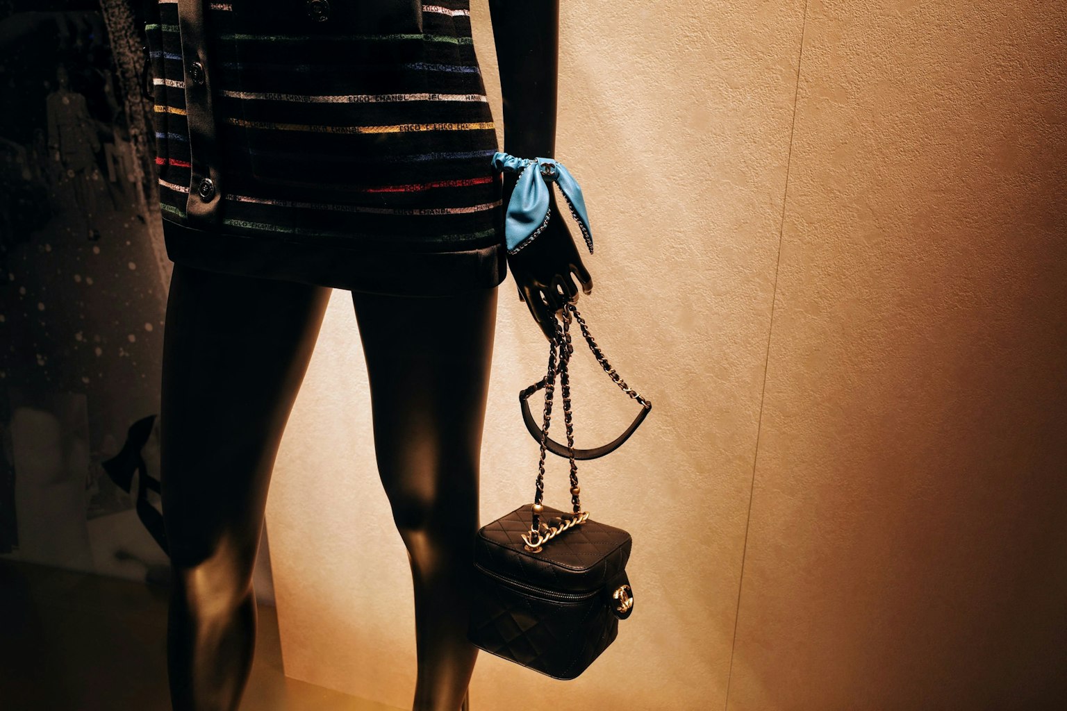 Mannequin portant un haut rayé tenant un bandeau bleu et un sac à main noir