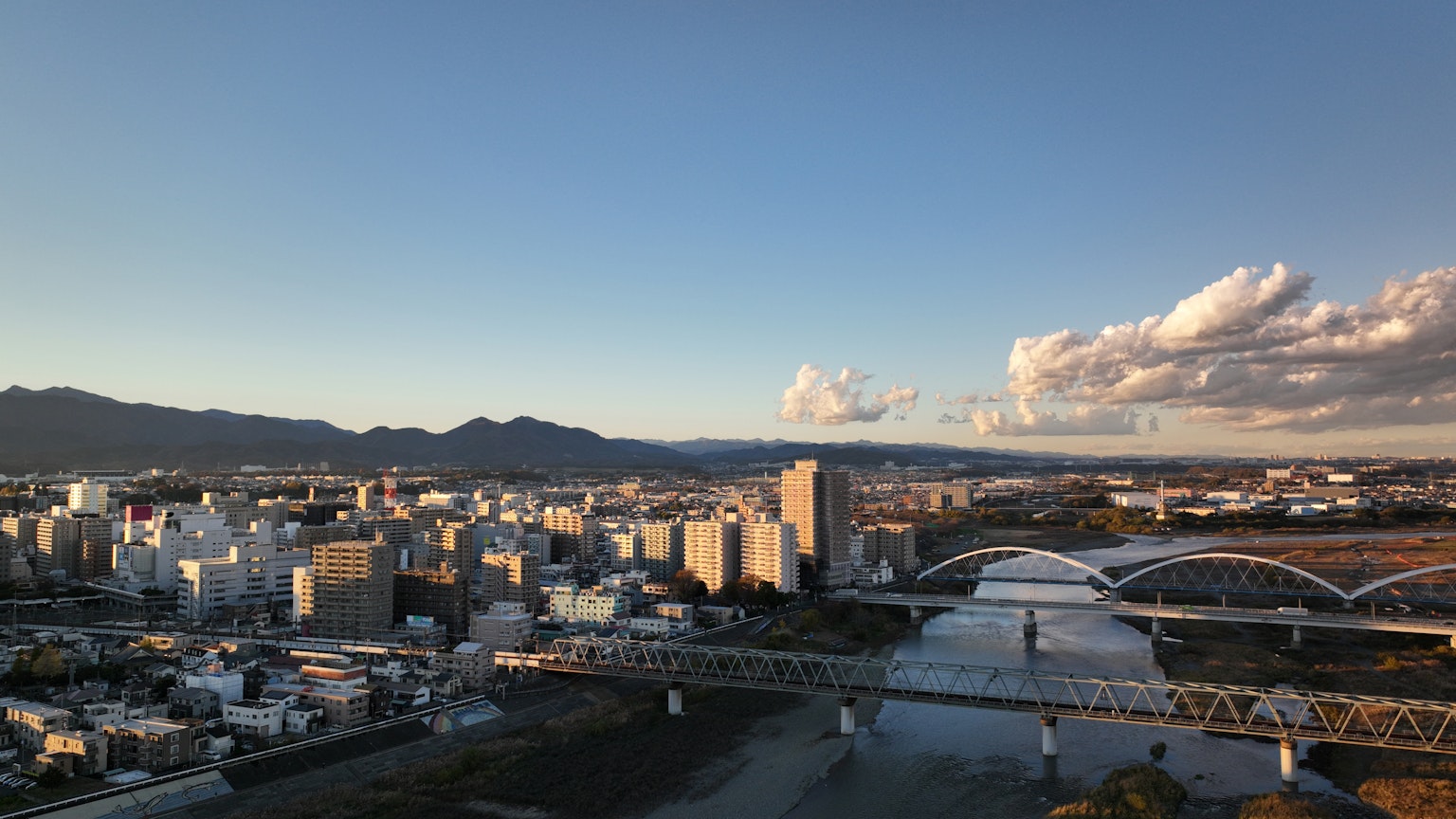 Paysage urbain avec des immeubles de grande hauteur et un pont sur une rivière sous un ciel bleu avec des nuages blancs