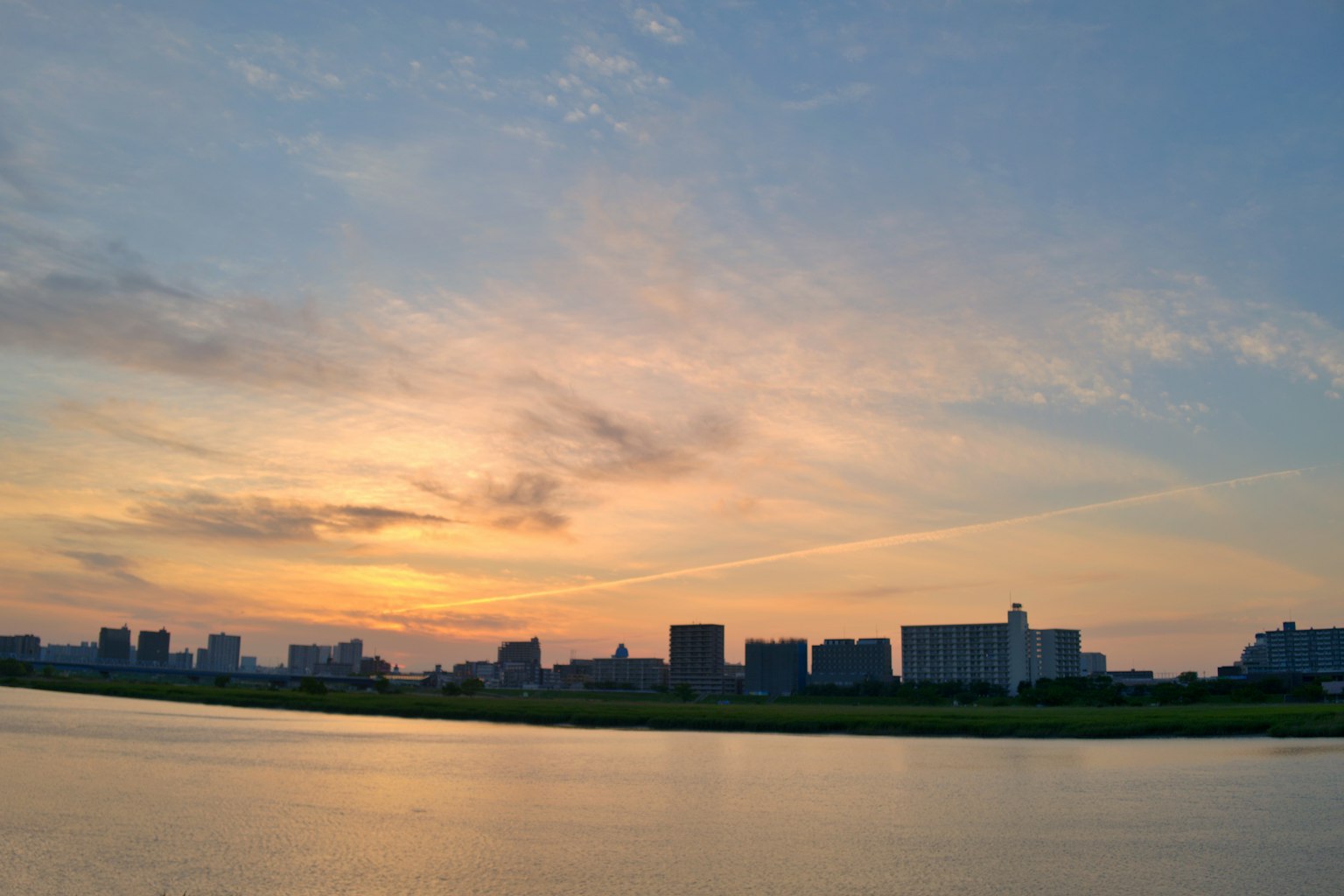 Silhouette d'une ville au coucher du soleil avec des reflets sur l'eau calme