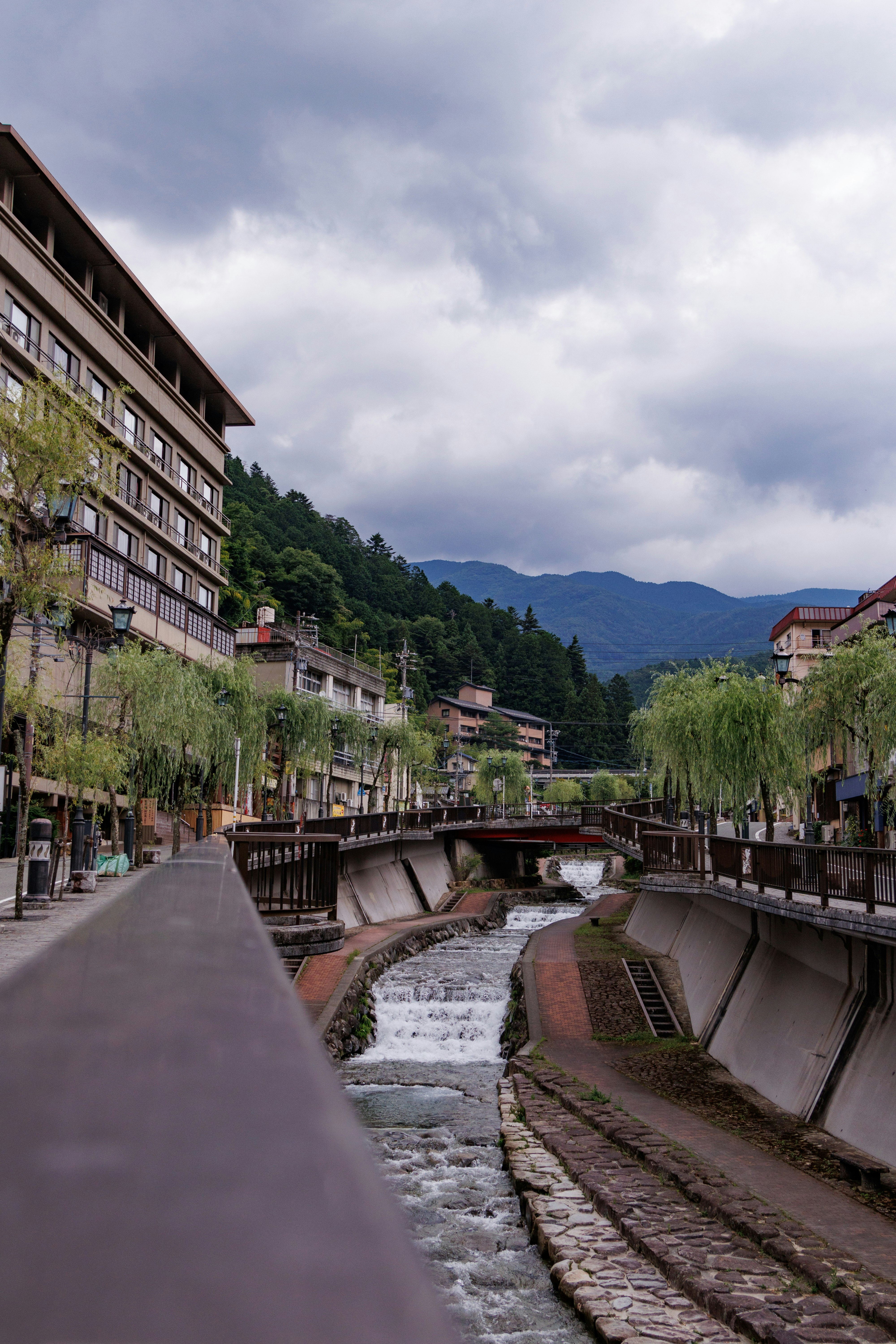 川沿いの遊歩道と石畳の水路、山並みを望む街並み