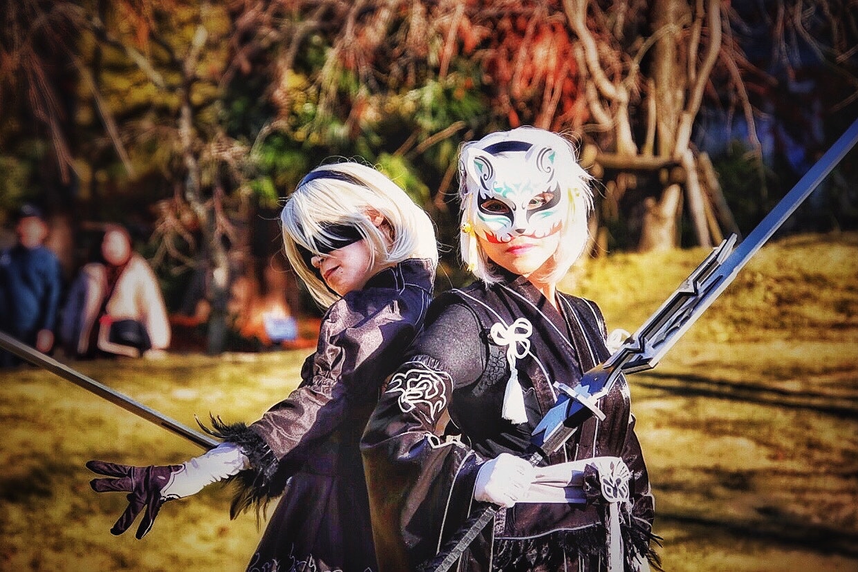 草地で剣を構えるコスプレイヤー2人の屋外撮影