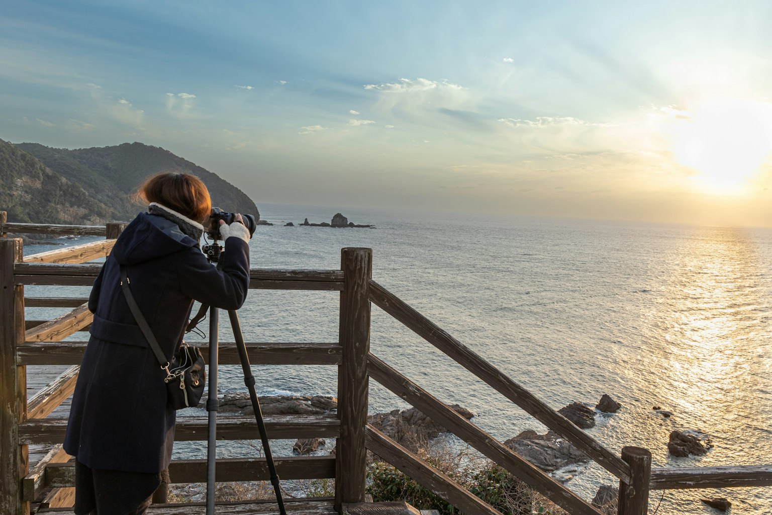 Person, die den Sonnenuntergang an der Küste mit einer Kamera fotografiert