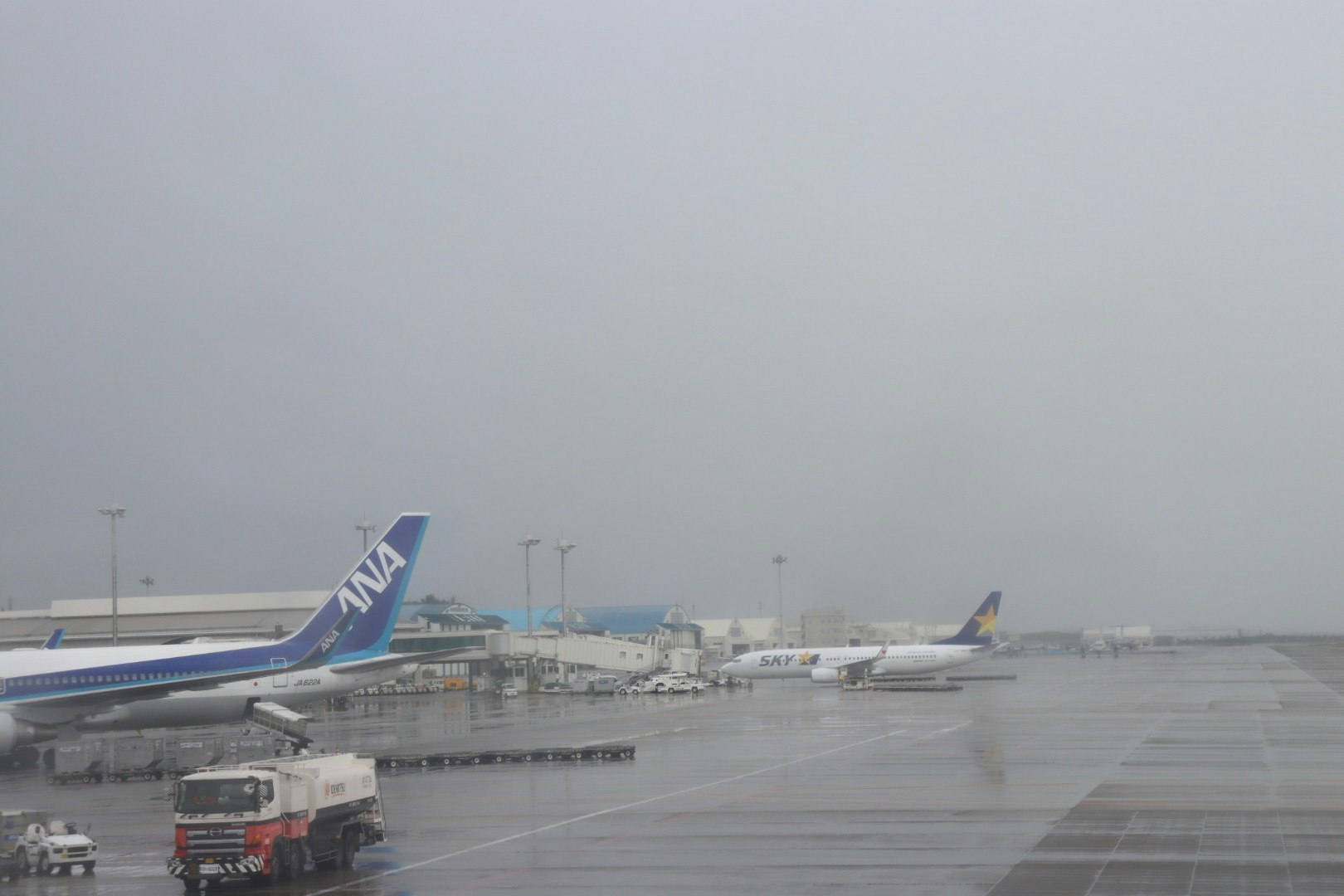 雨の滑走路で飛行機が並ぶ空港の風景