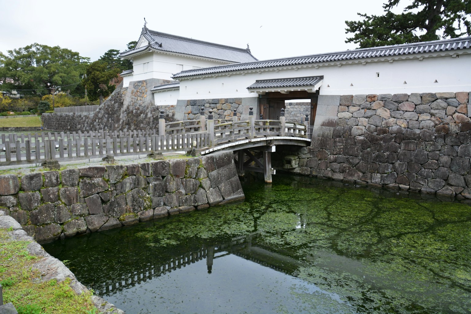 Japanese castle entrance with a stone bridge and pond