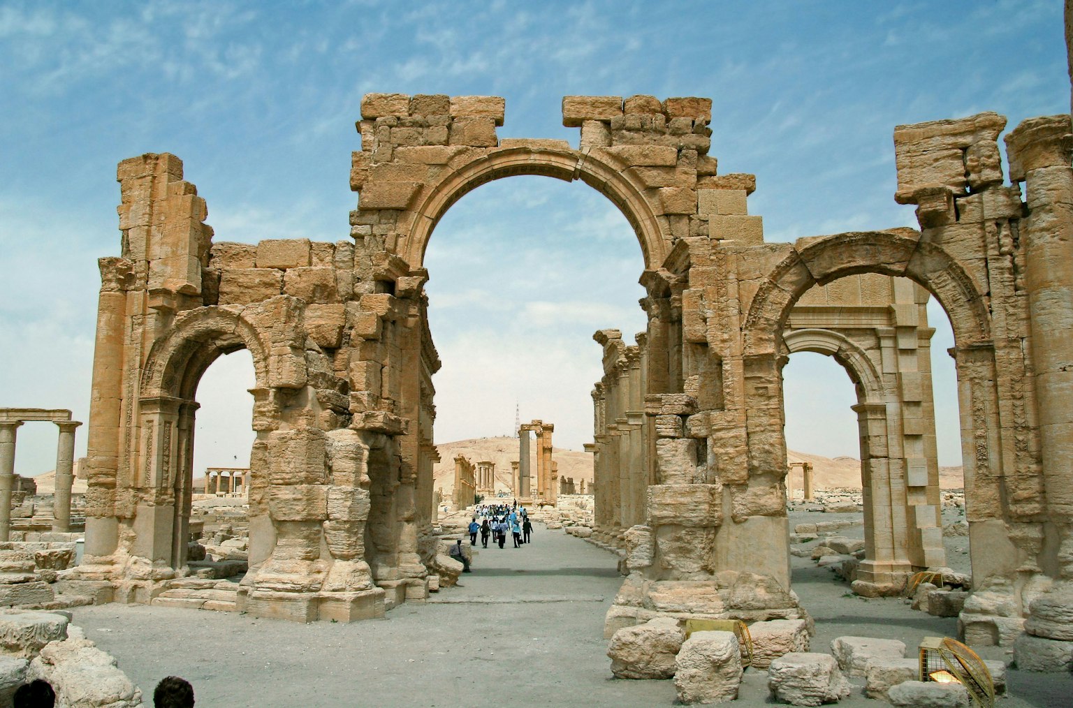 Ancient ruins featuring an arch and columns against a blue sky