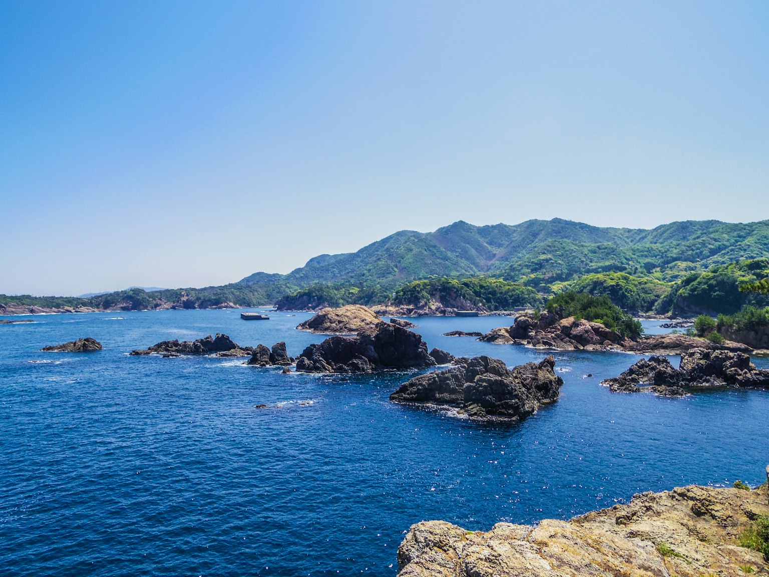 Vista panoramica dell'oceano blu e delle montagne verdi con una costa rocciosa