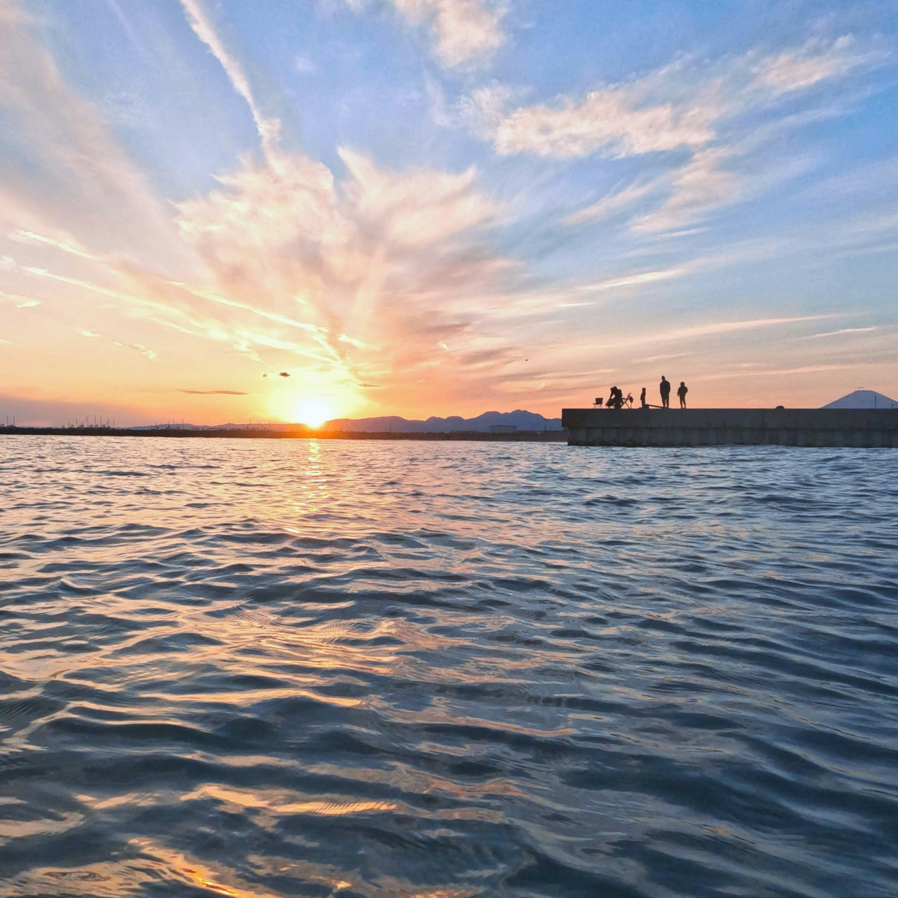 夕日に照らされた海辺で人がボートに乗る風景