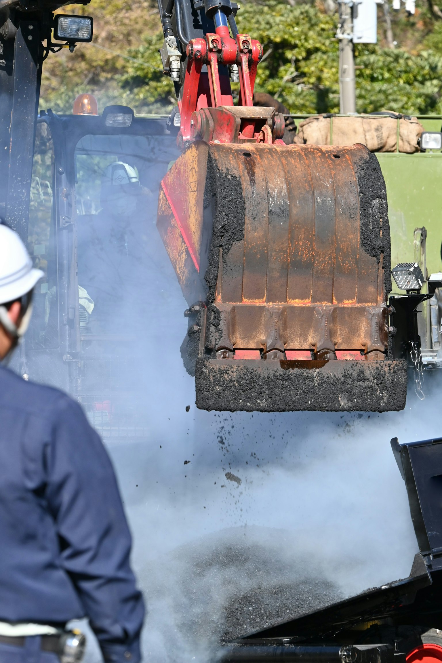 Escavatore che lavora in un cantiere con fumi che si alzano