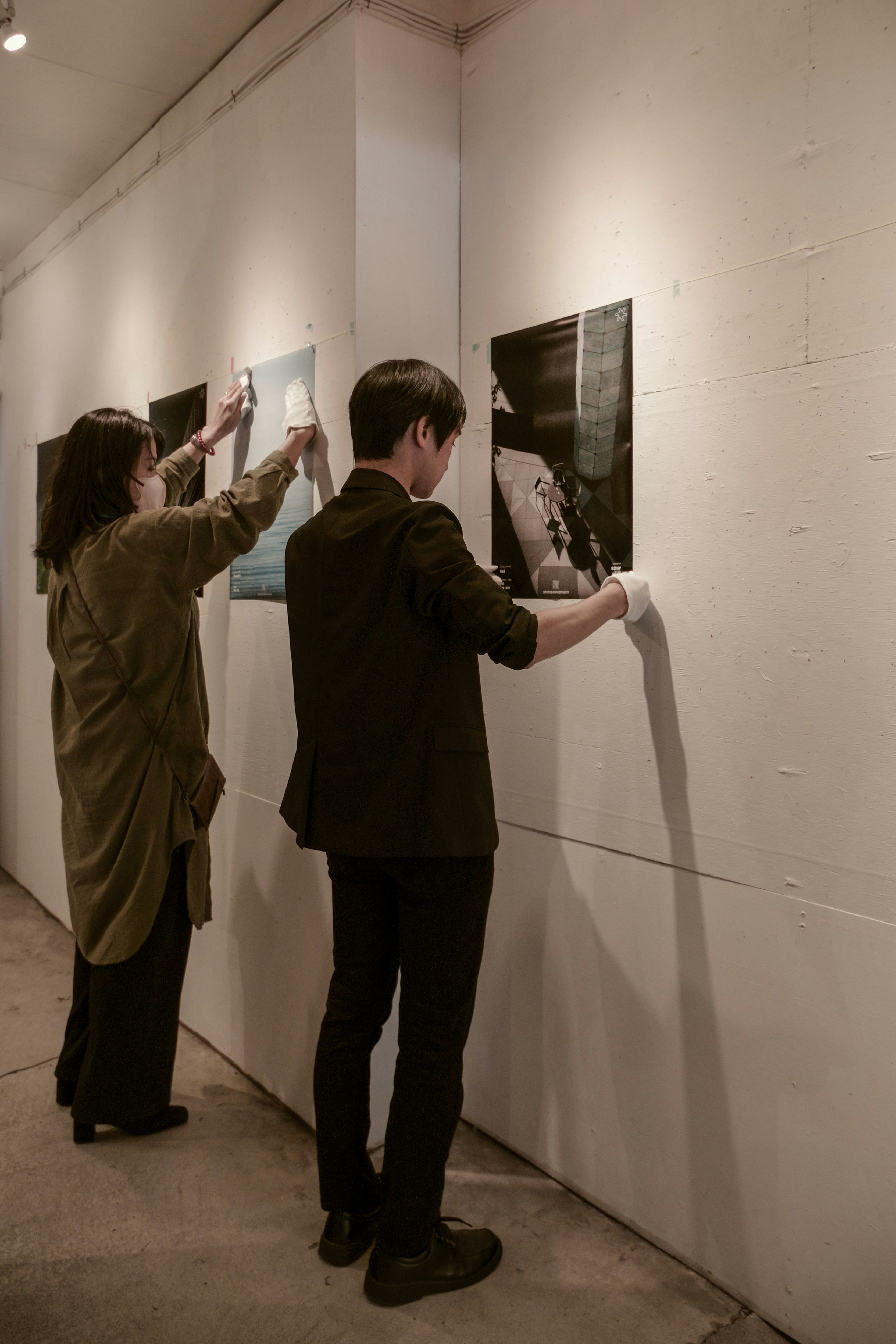 展示会場で壁面に作品を取り付ける設営スタッフの様子（東京・浅草橋）