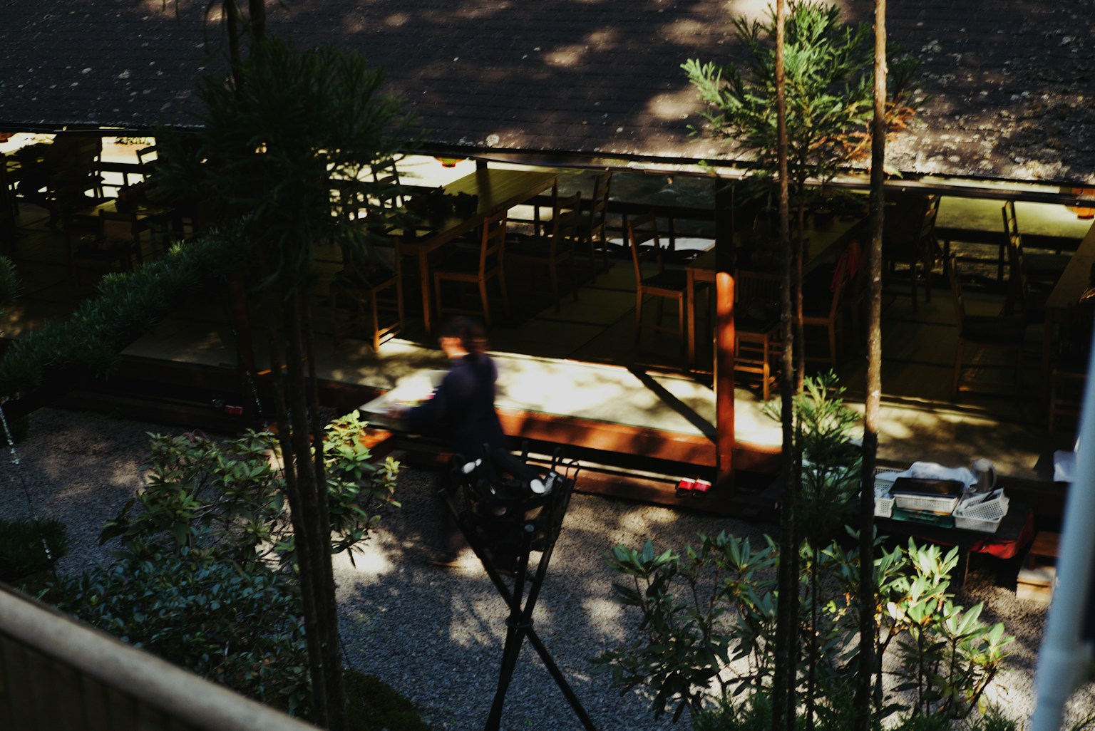 Cafe terrace with shadows and a person walking