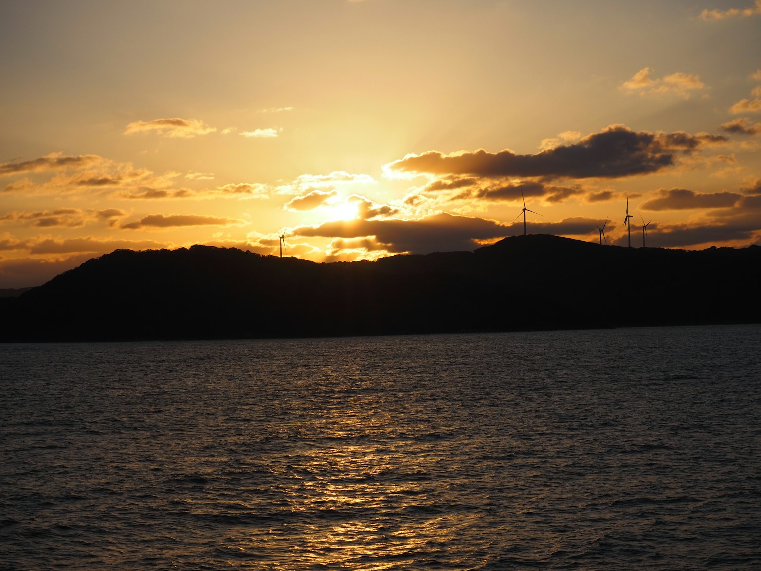 Sonnenuntergang über dem Ozean mit silhouettierten Bergen