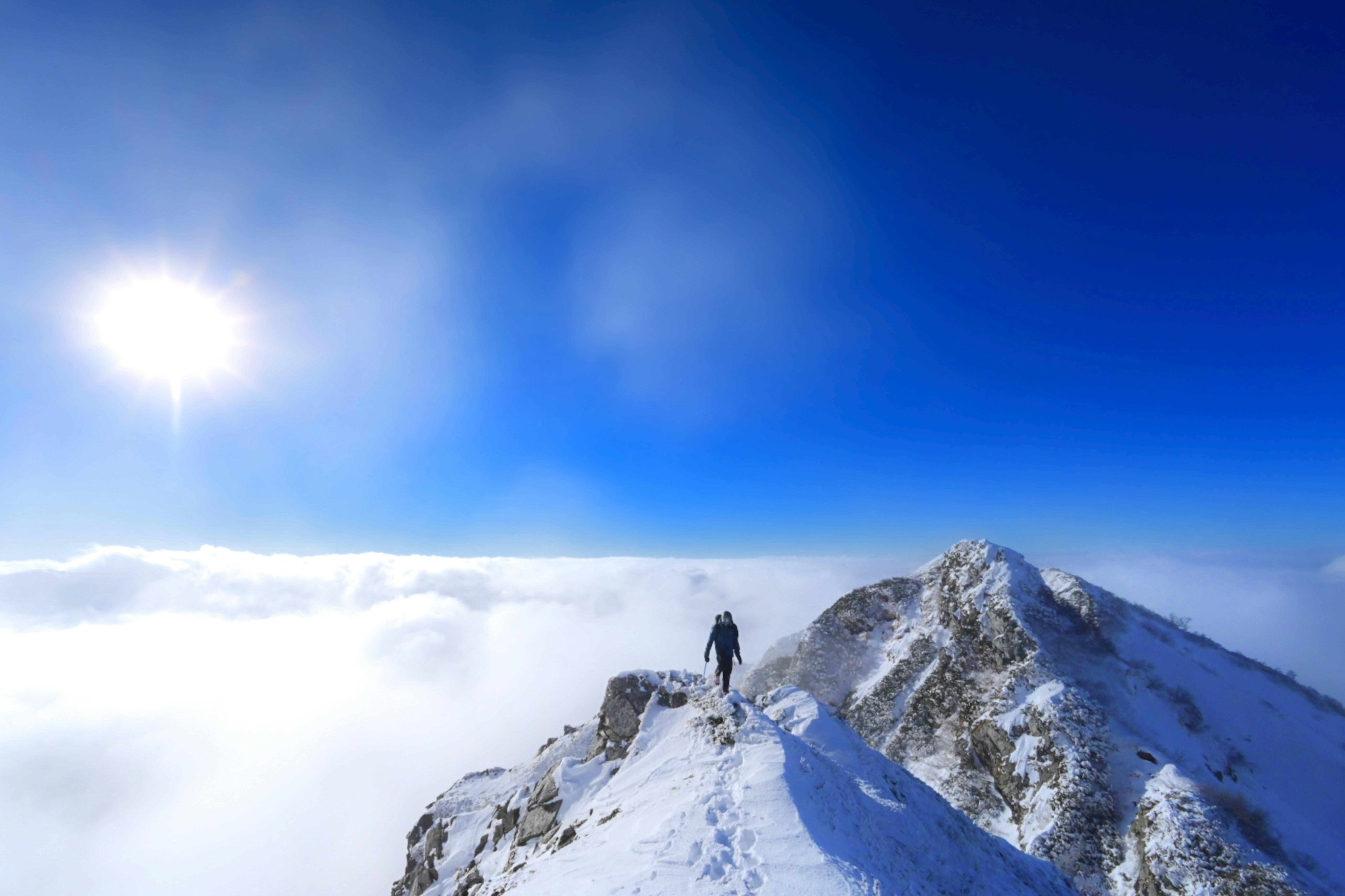 雲海の上にそびえる剱岳の雪山稜線を歩くセルフポートレート