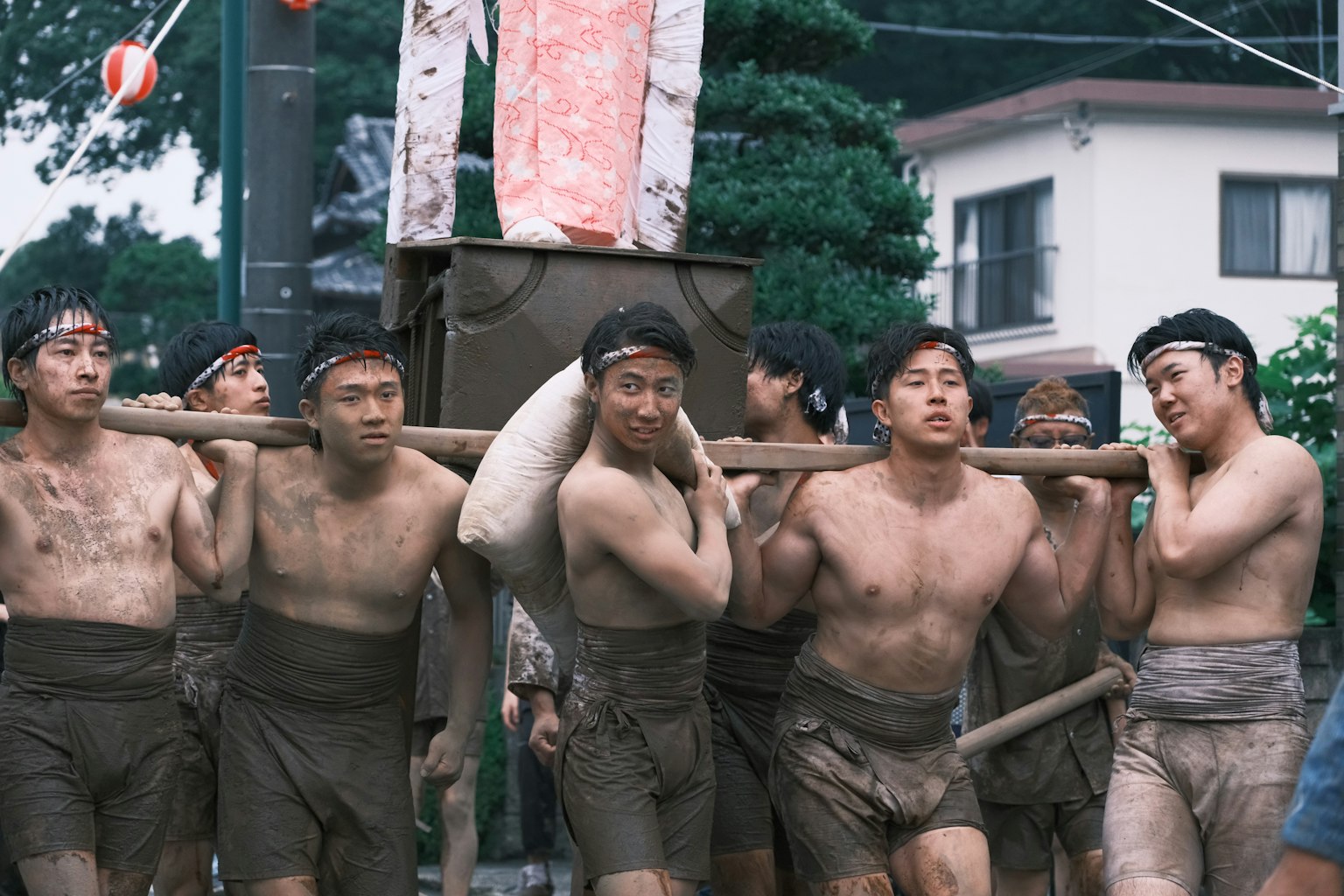 在傳統節日中搬運重物的男人們，滿身泥土