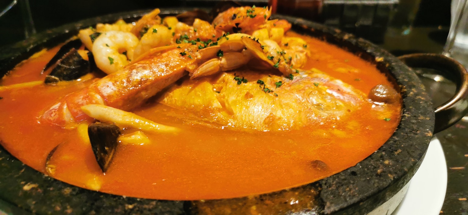 Ragoût de fruits de mer servi dans une poterie en pierre avec des fruits de mer frais et une sauce à base de tomate