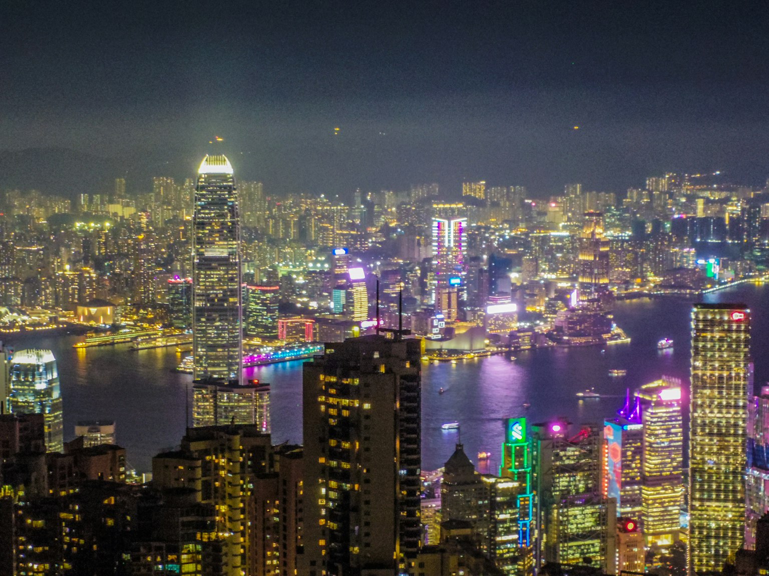 Pemandangan malam yang menakjubkan dari Hong Kong dengan gedung pencakar langit yang diterangi dan pelabuhan