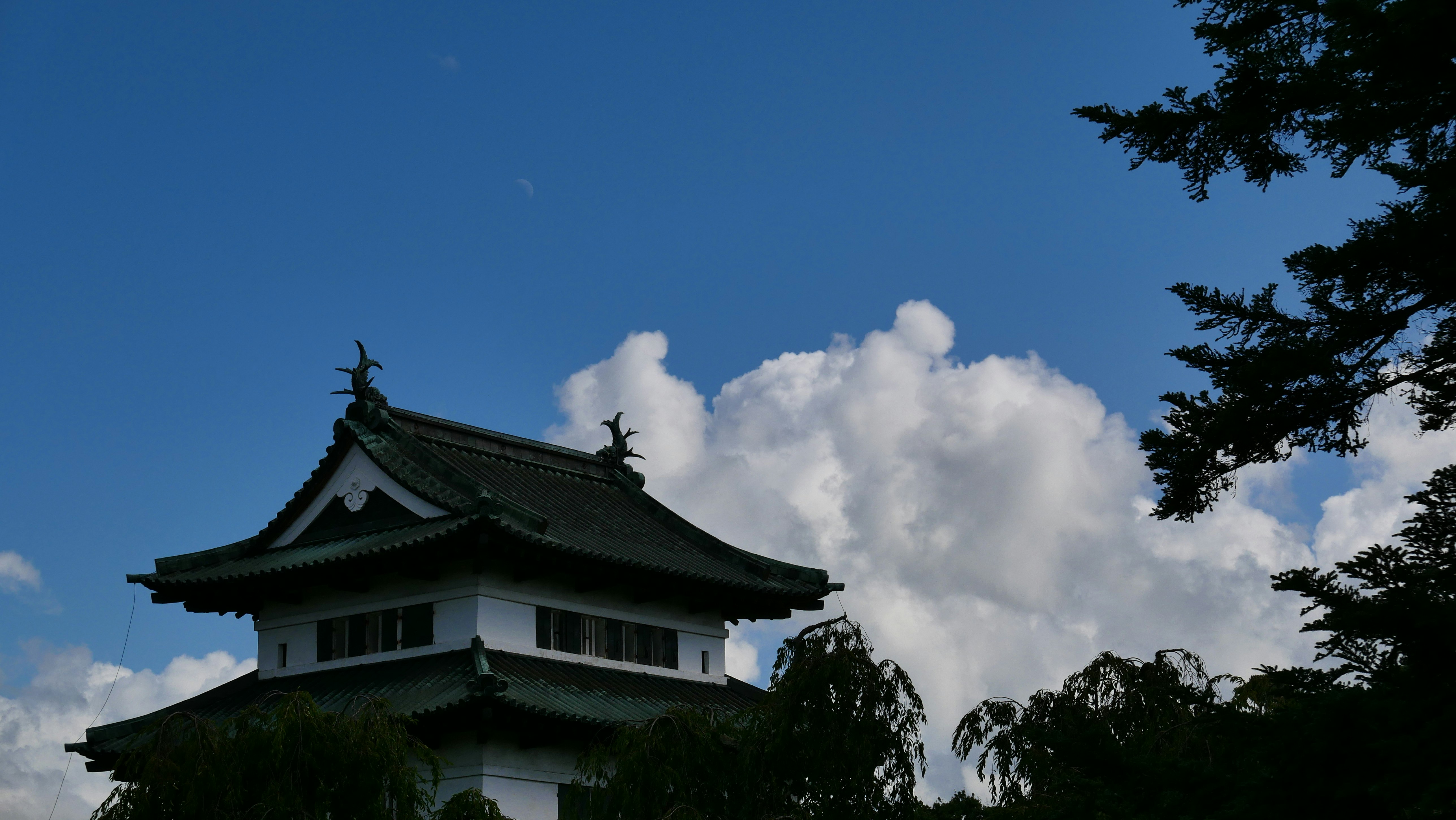 雲が立ちのぼる古い瓦屋根の建物