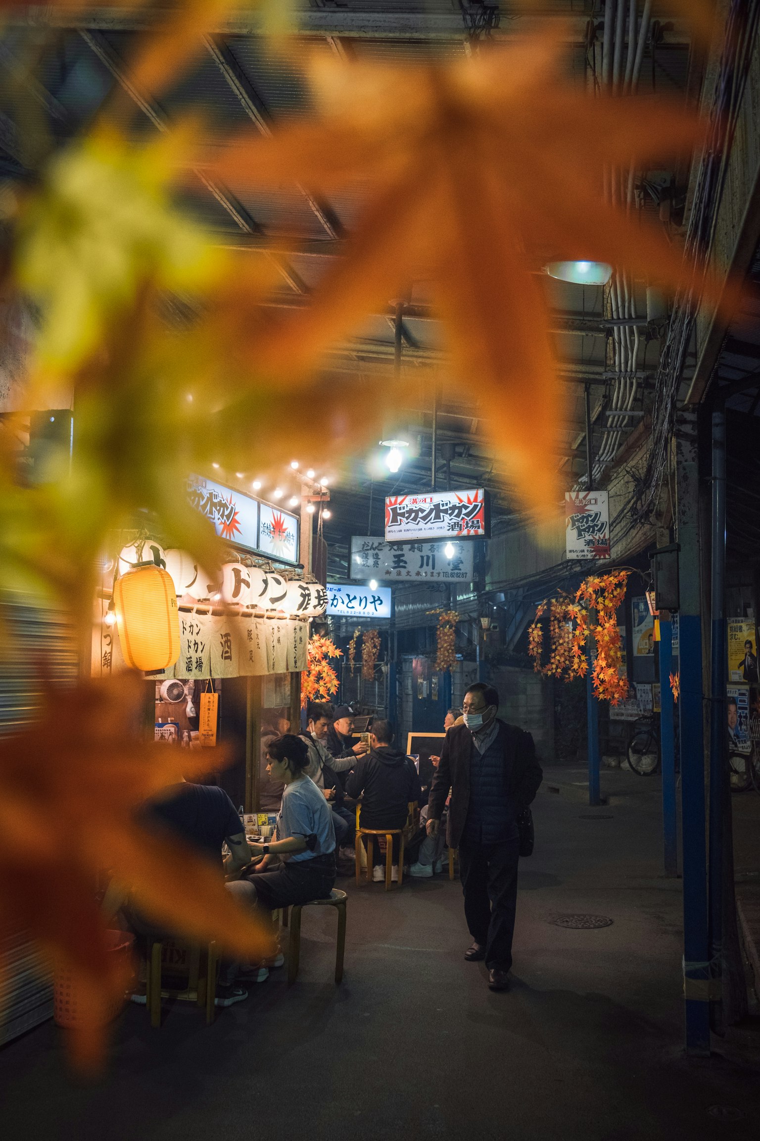 前景中的秋天叶子和热闹的夜市及食品摊位
