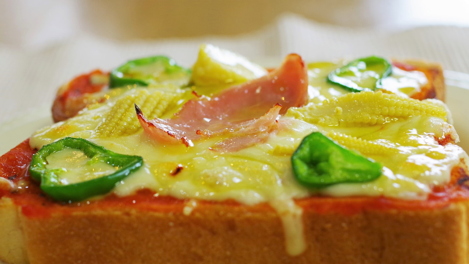 Bread topped with cheese, ham, and green peppers