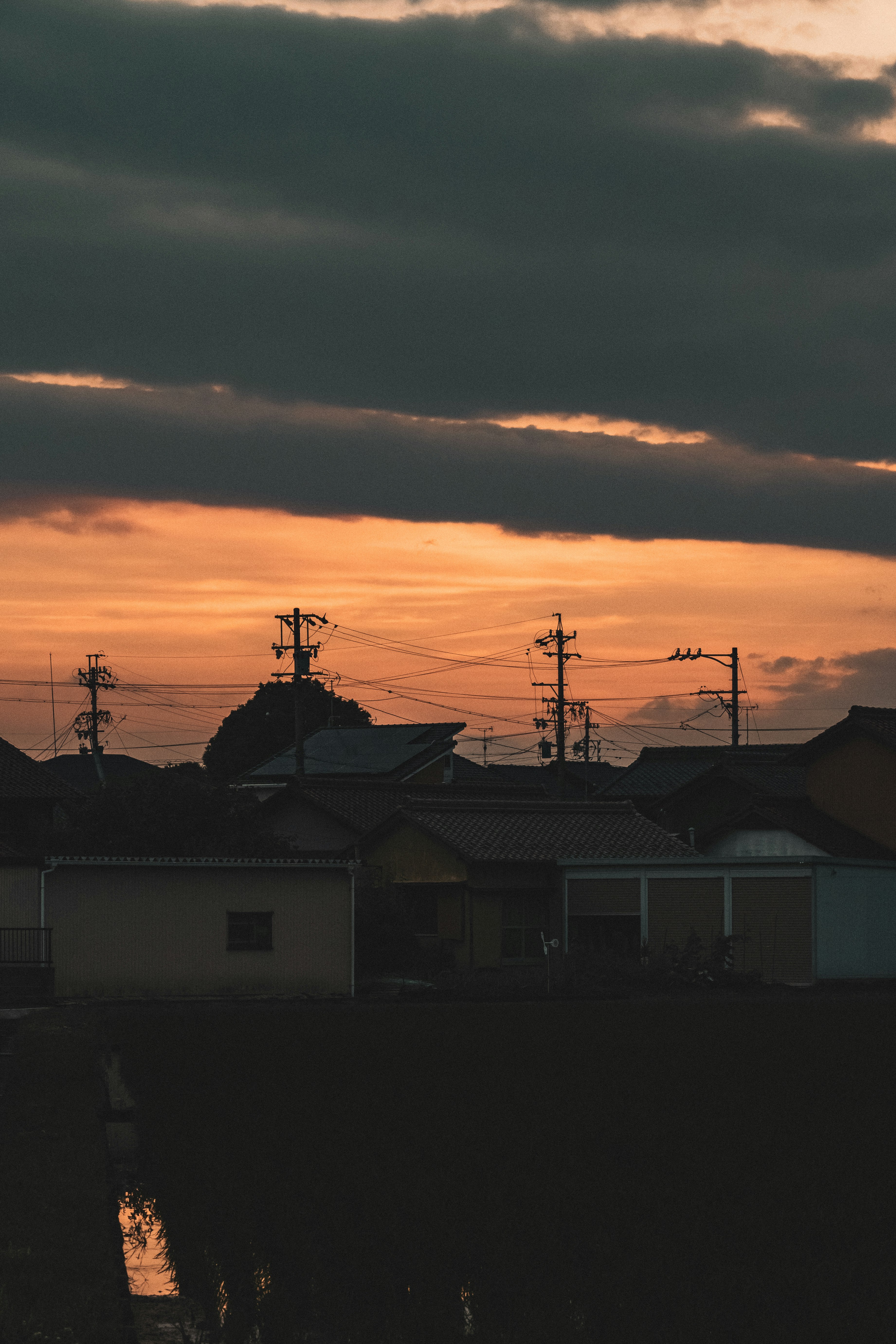 夕焼けの空と電線が走る住宅街の屋根