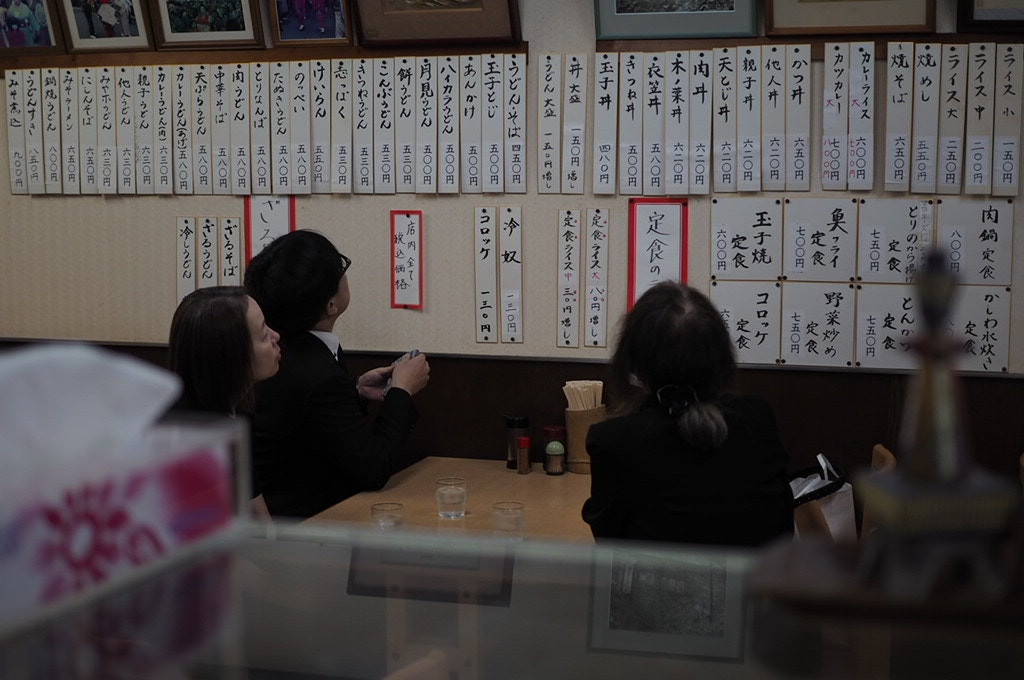 書道の短冊が並ぶ店内で客が席に座る様子