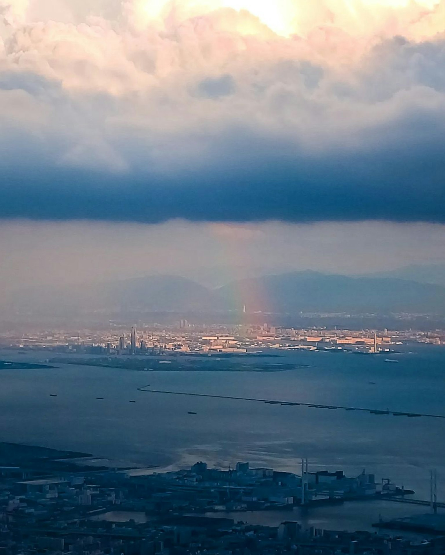 Vista delle luci della città e di un arcobaleno visibile tra le nuvole