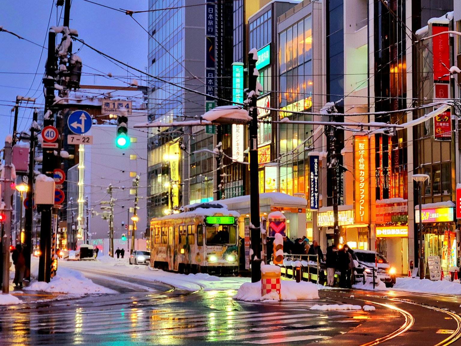 Snow-covered city street with tram and illuminated buildings