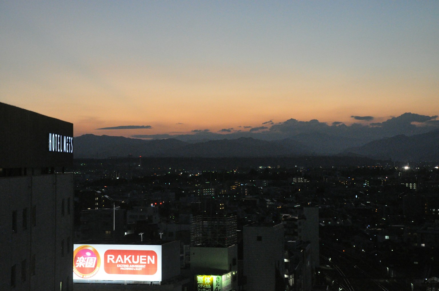 Cityscape at dusk with silhouetted mountains in the background