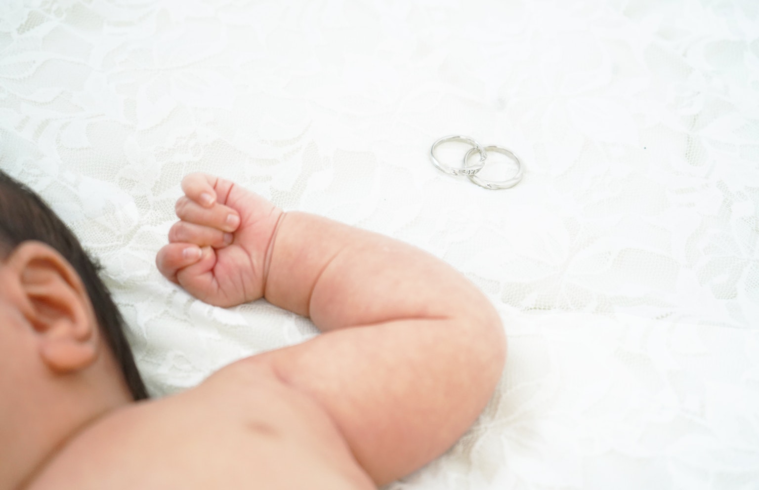 Lengan bayi dengan cincin pernikahan di sampingnya
