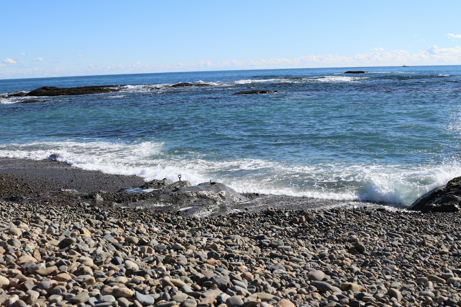 Ruhige Küstenszene mit Kiesstrand und blauem Ozean