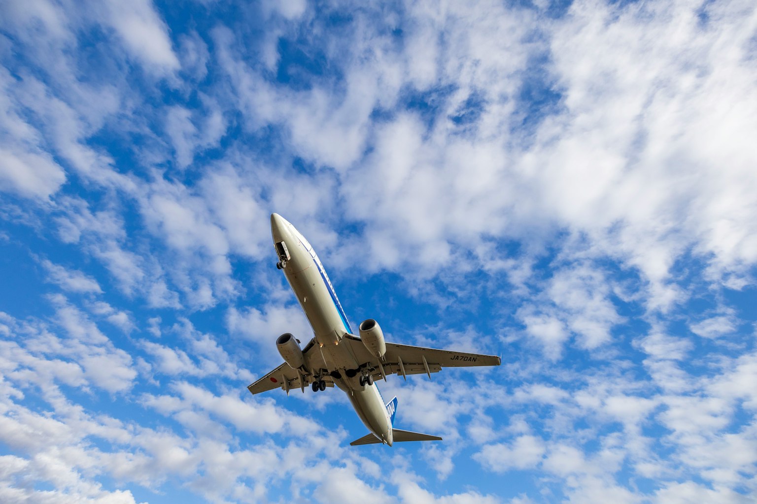 An airplane flying against a blue sky with clouds