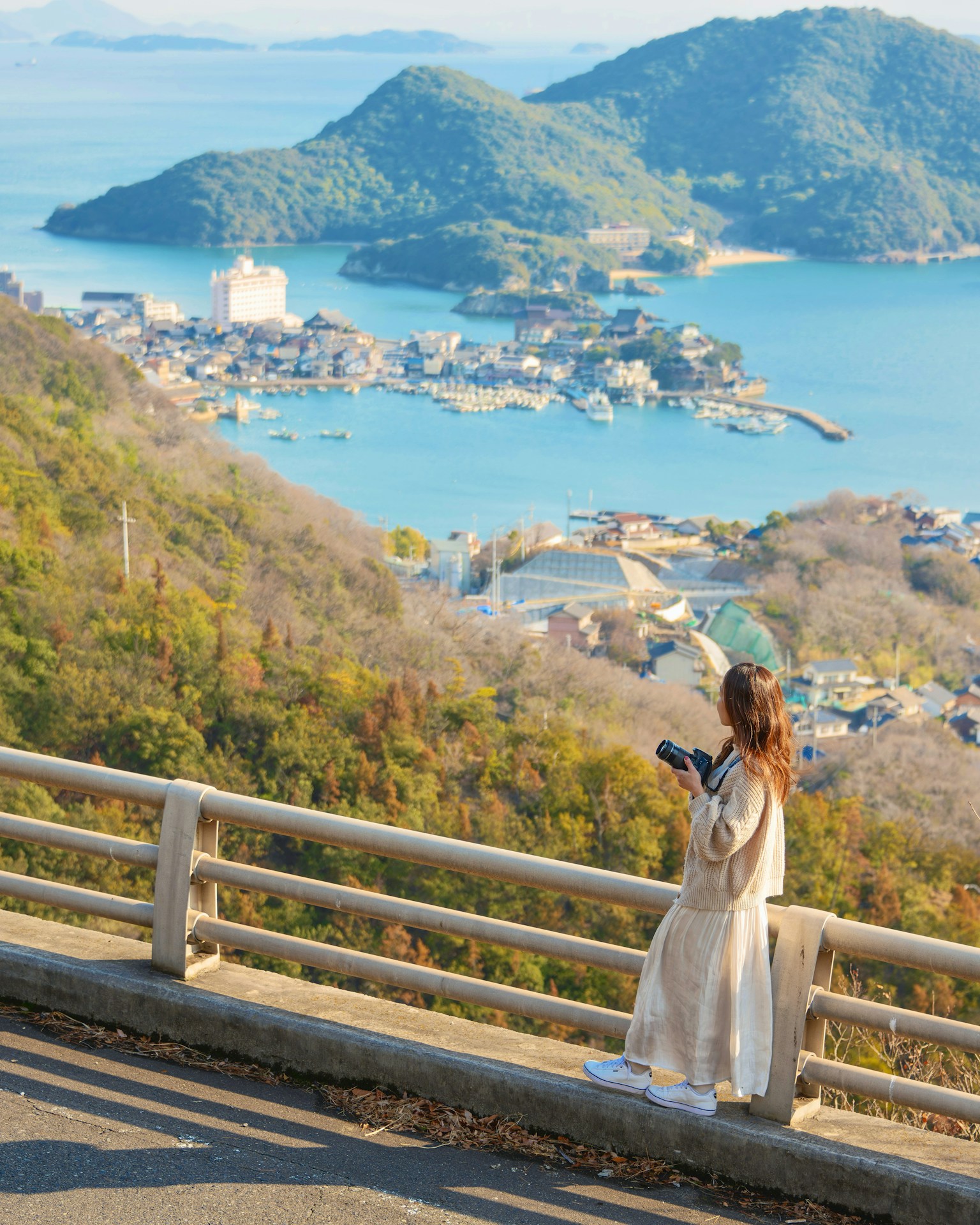 海を背景にした女性がカメラを持っている風景