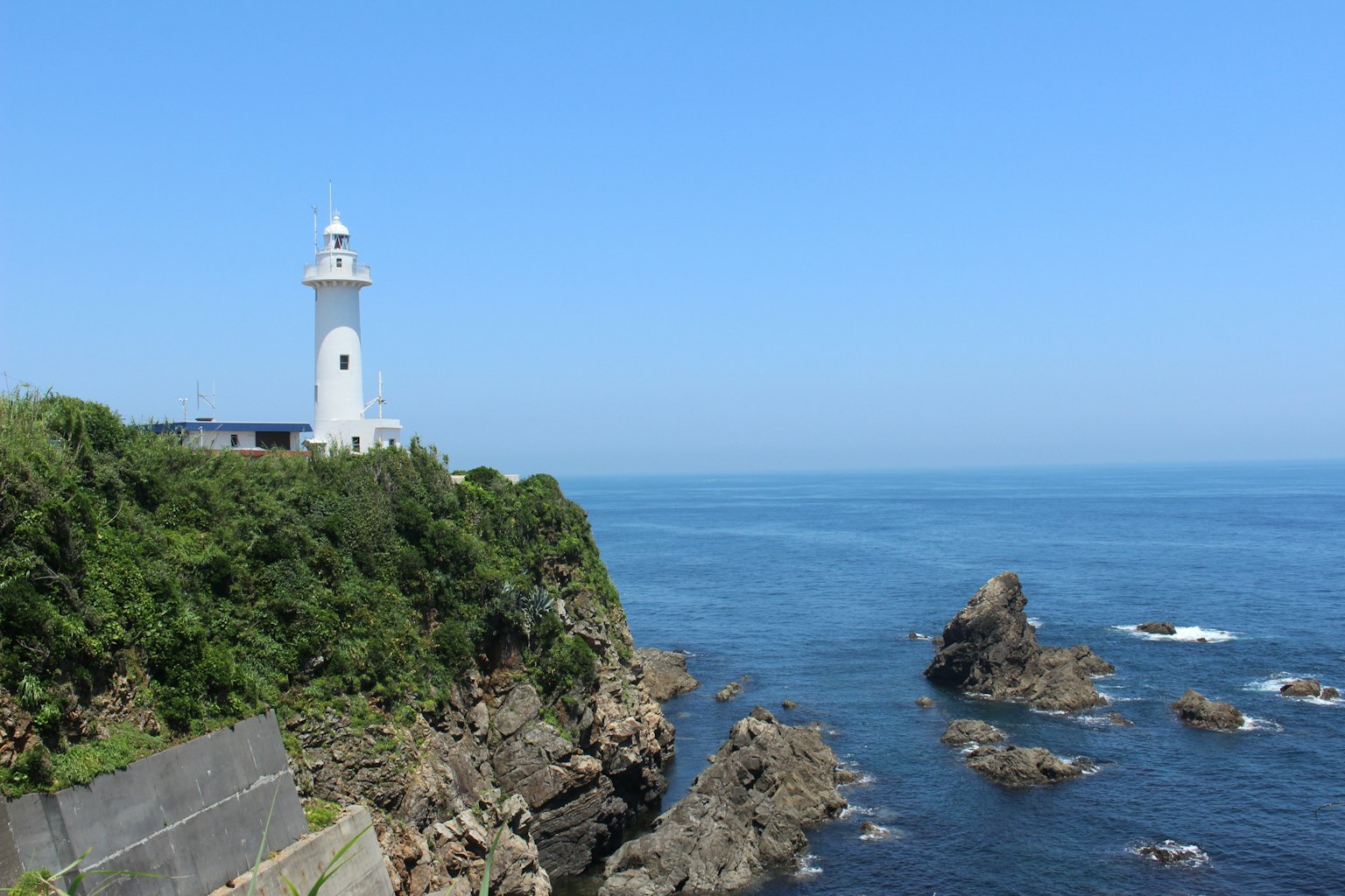 悬崖上的白色灯塔与蓝色海洋和岩石的风景