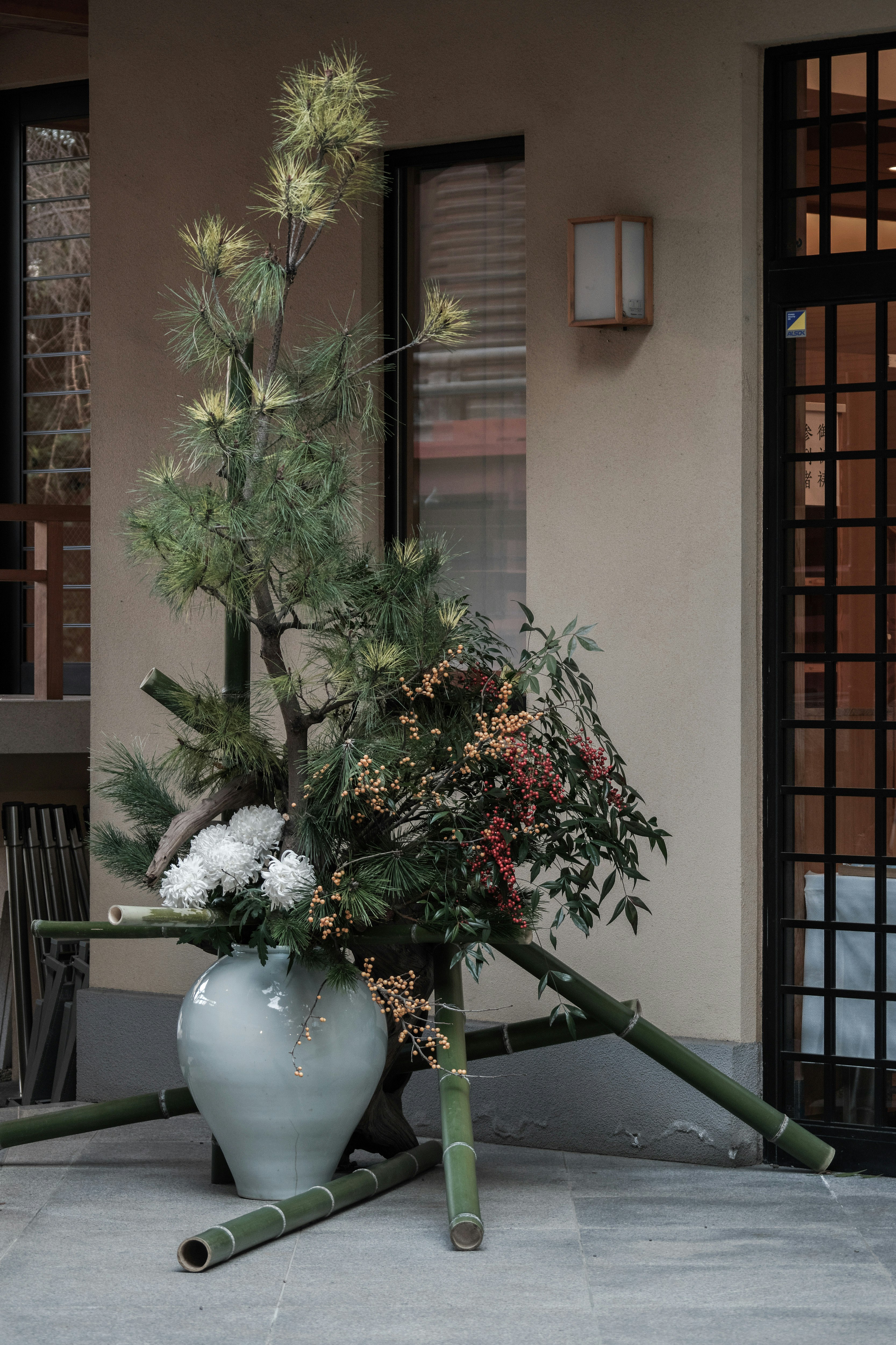 Composizione di ikebana dinamica con vaso e steli di bambù su pavimento interno