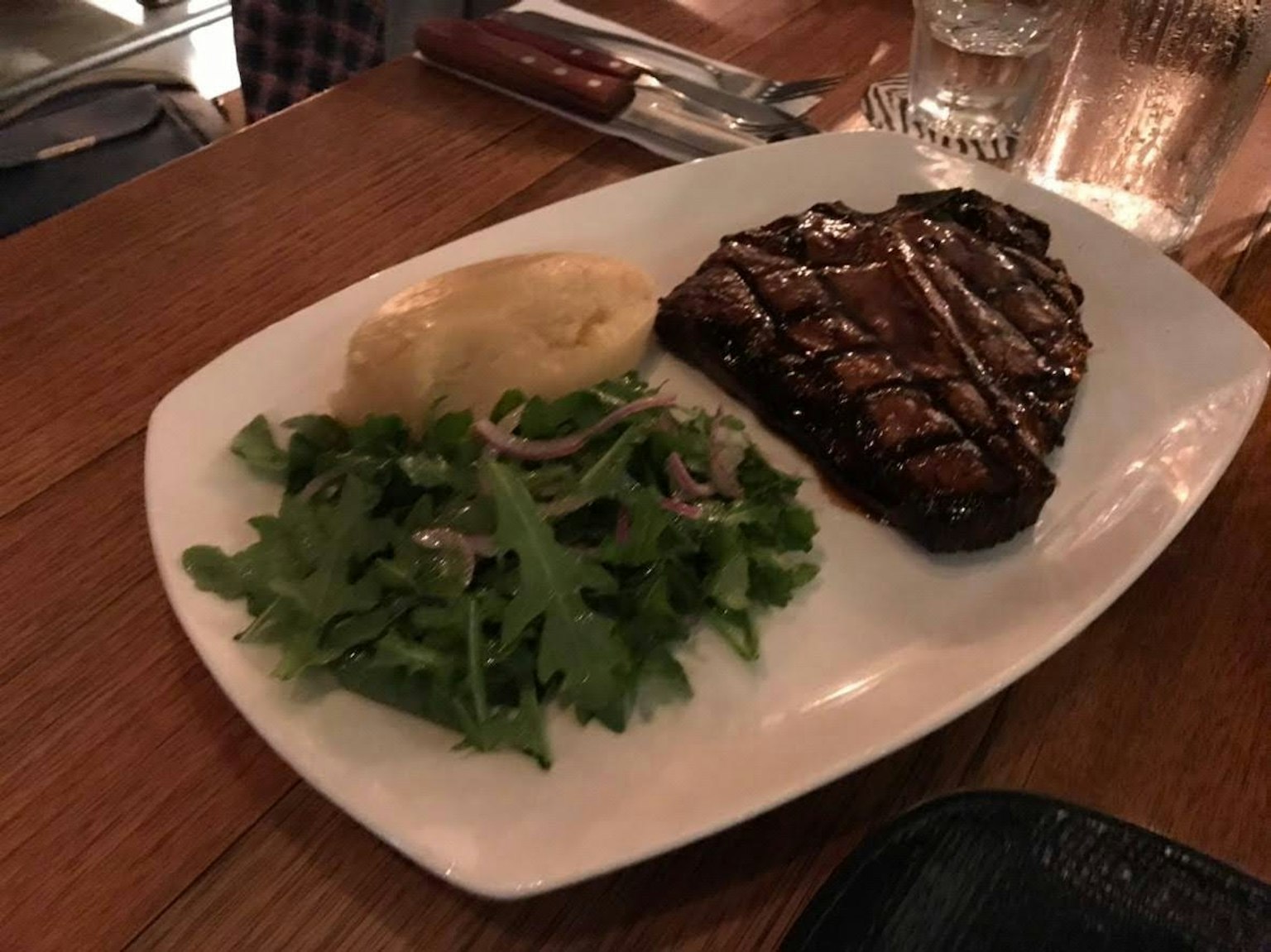Bistecca alla griglia con insalata e purè di patate su un piatto