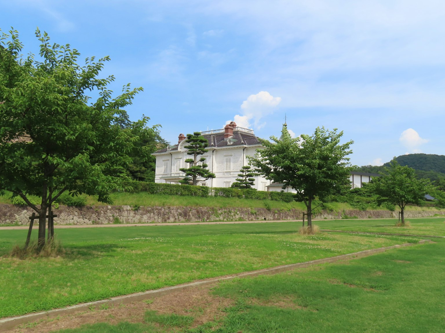 Paesaggio con un edificio bianco circondato da erba verde e alberi