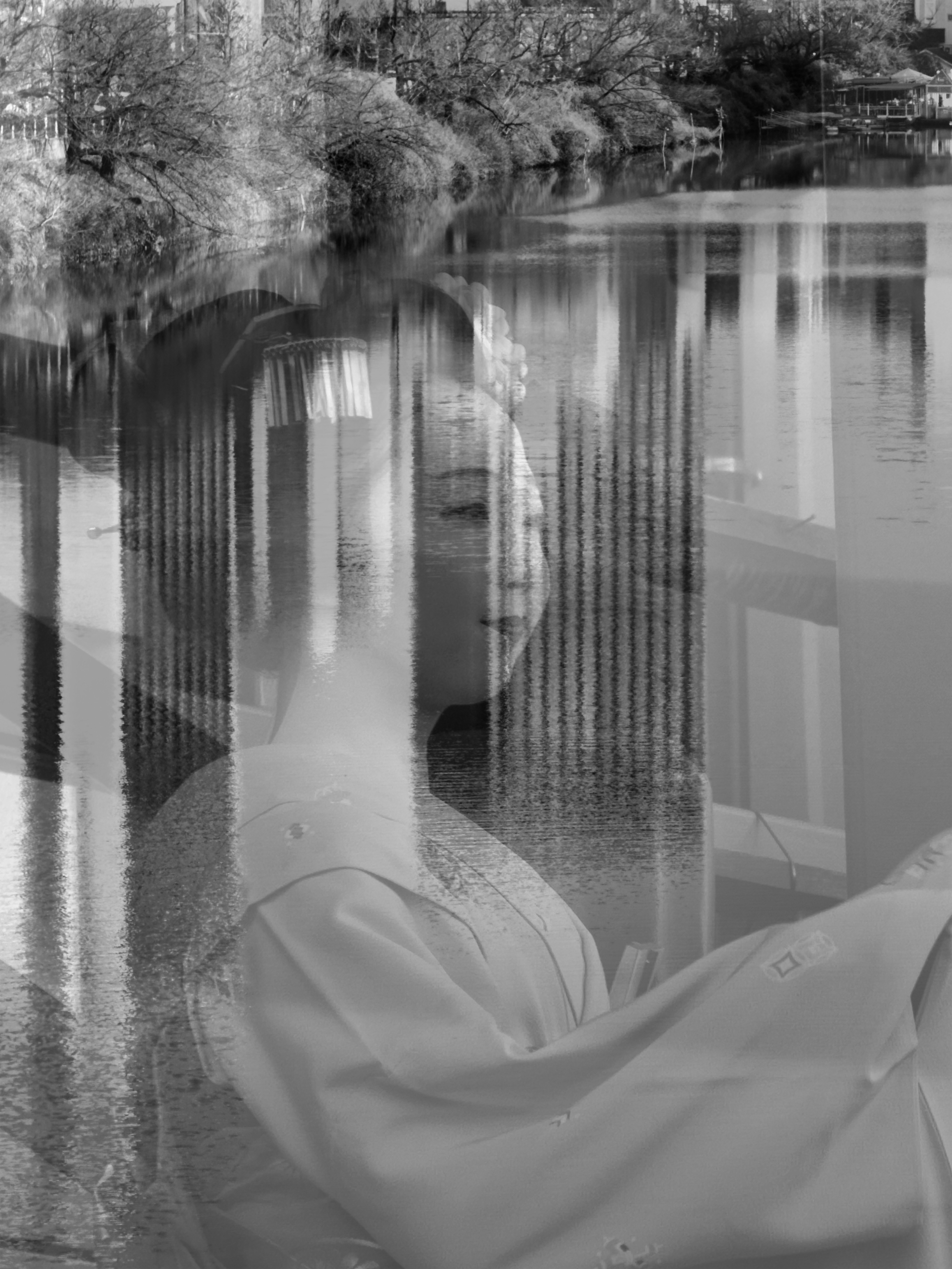 白黒の写真に映る日本の女性が伝統的な着物を着ている 背景には水面と木々が見える